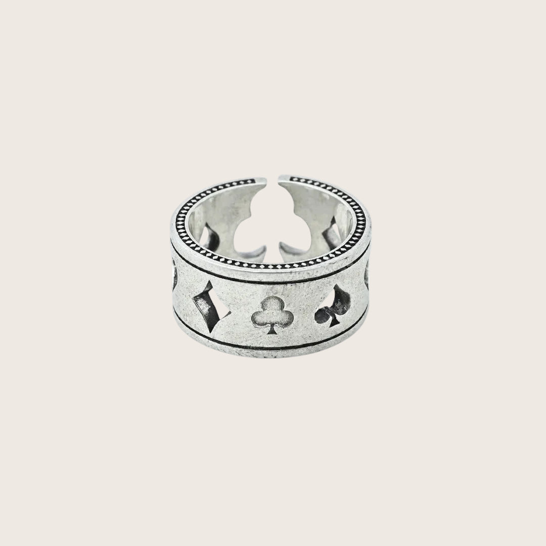 Silver ring with playing card suits on a white background, branded 'Trishnna'.