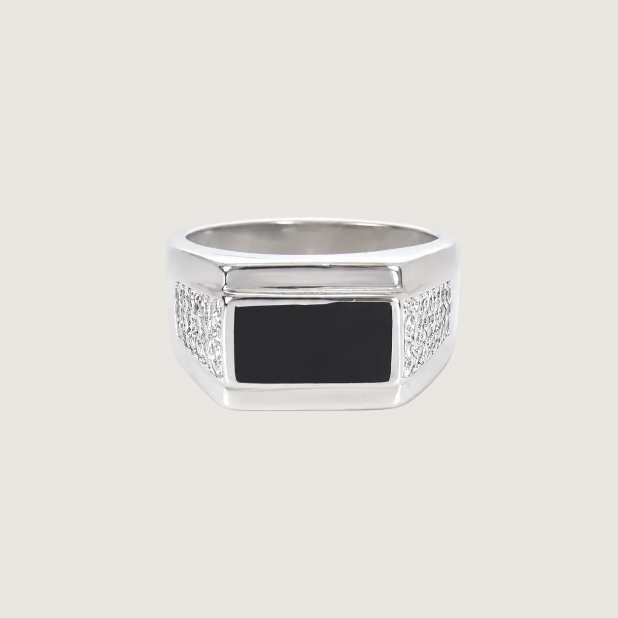 Silver ring with a black square stone on a beige background