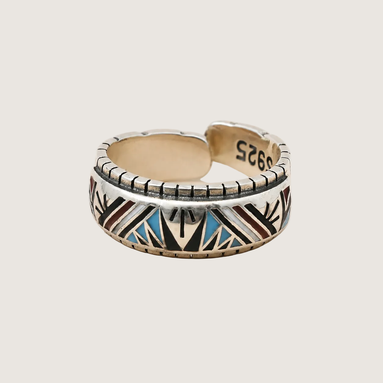 Silver ring with geometric pattern on a beige background