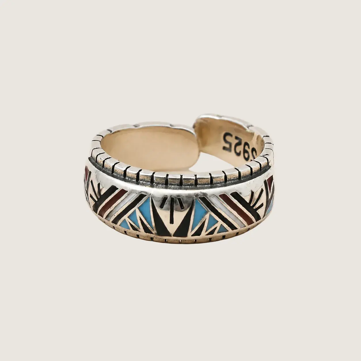 Silver ring with geometric pattern on a beige background