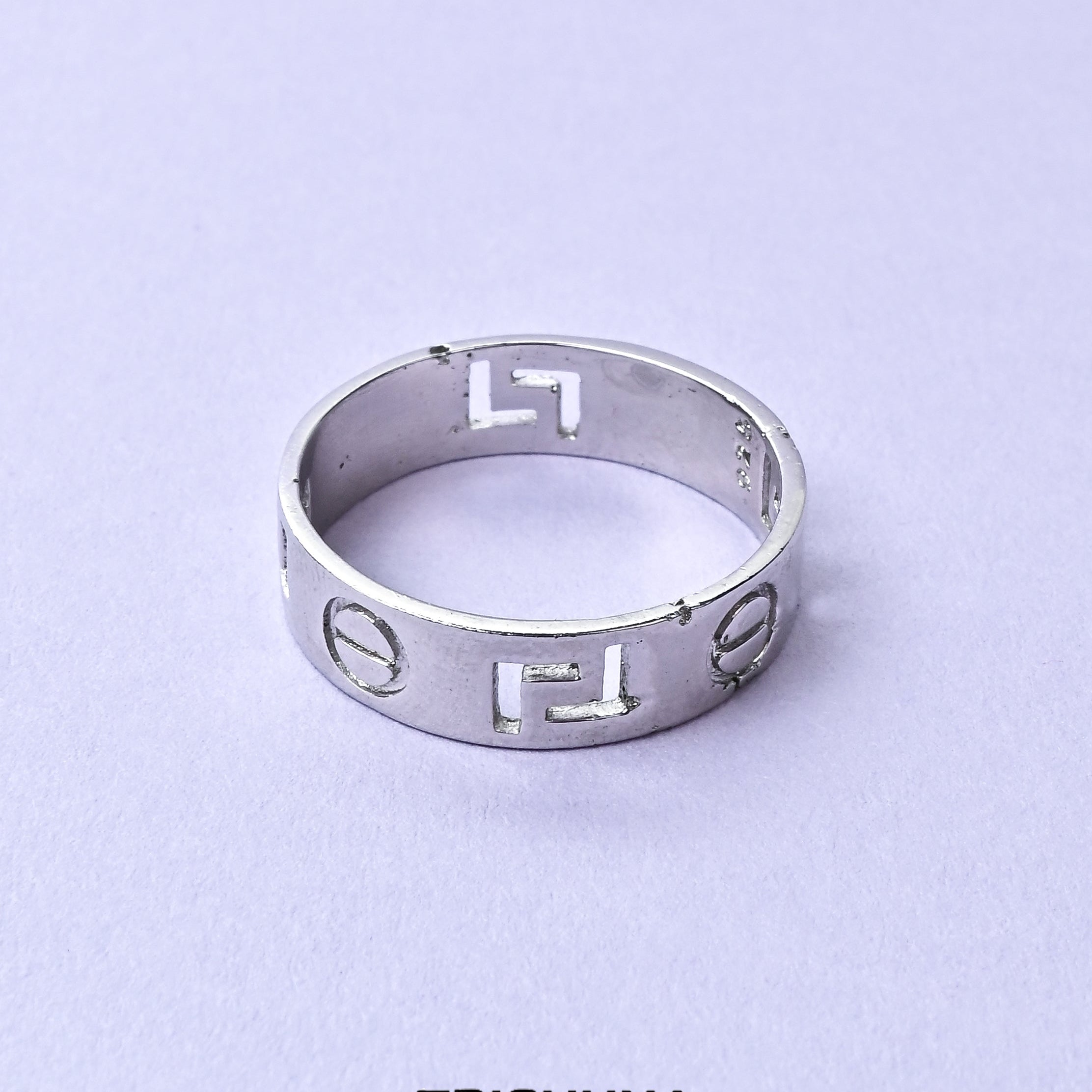 Silver ring with engraved symbols on a light purple background, featuring the brand 'TRISHNHA'.