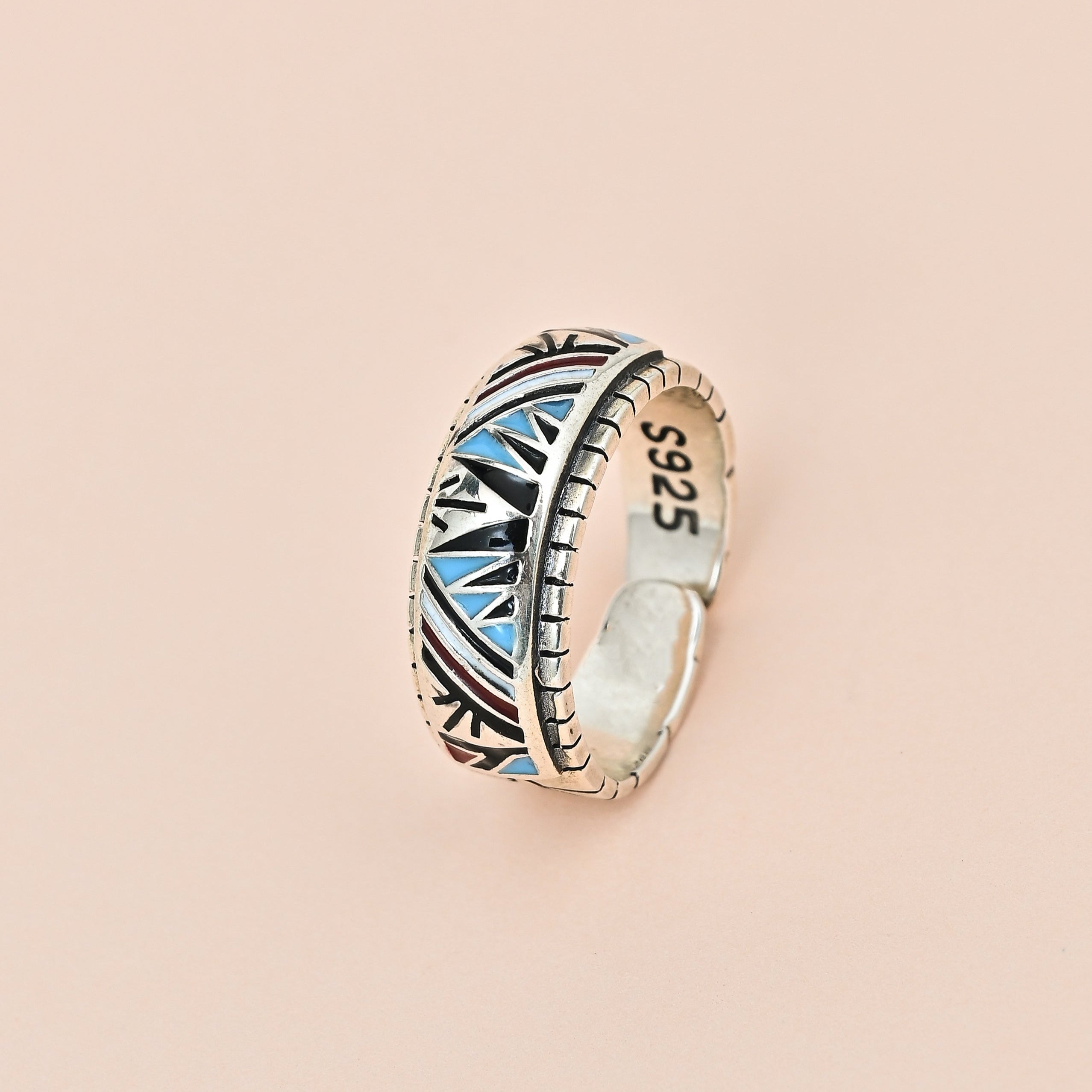Silver ring with blue accents on a beige background, featuring the brand 'TRISHNNA'.