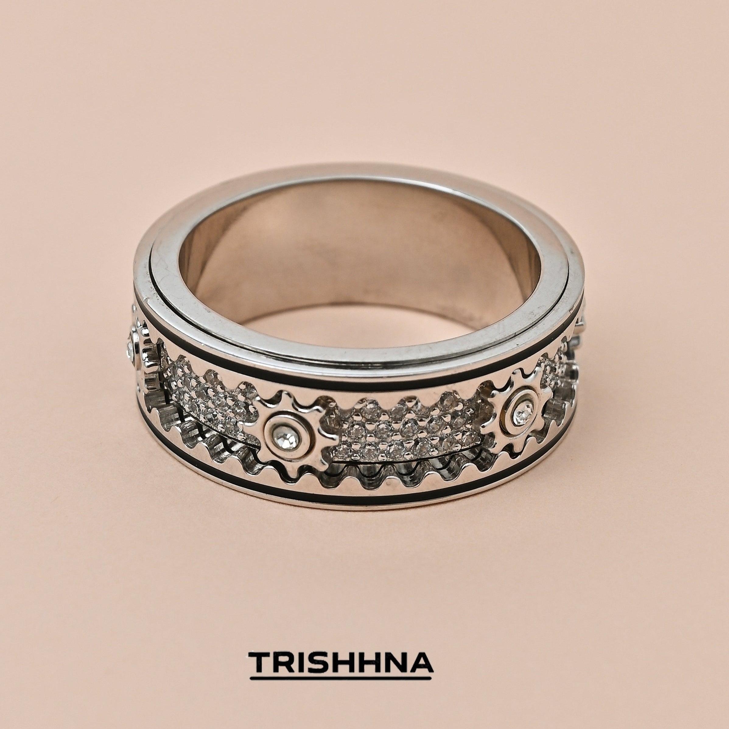 Decorative ring with intricate designs on a beige background, featuring the brand 'TRISHHNA'.