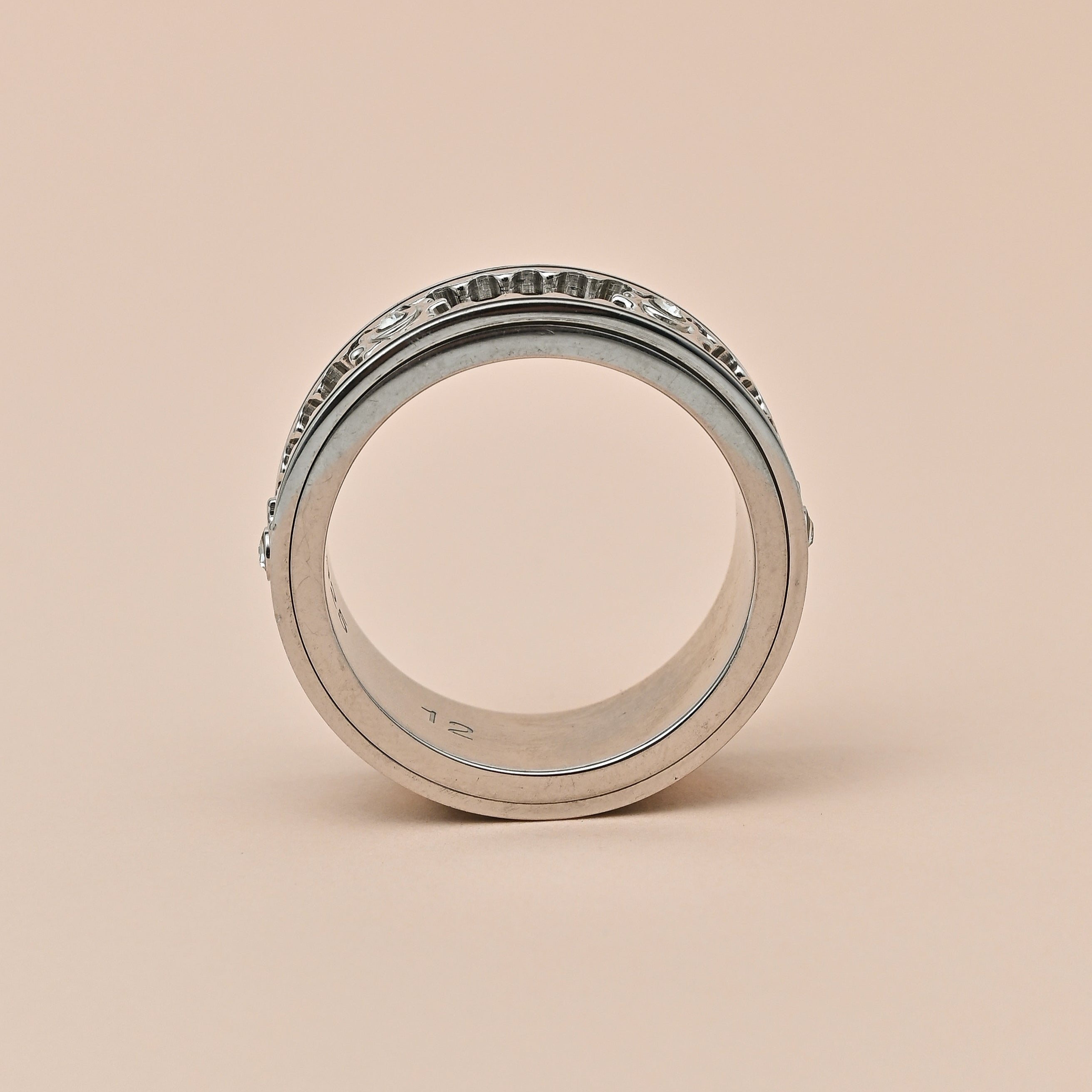 Silver ring with intricate design on a beige background, featuring the brand 'TRISHNNA'.