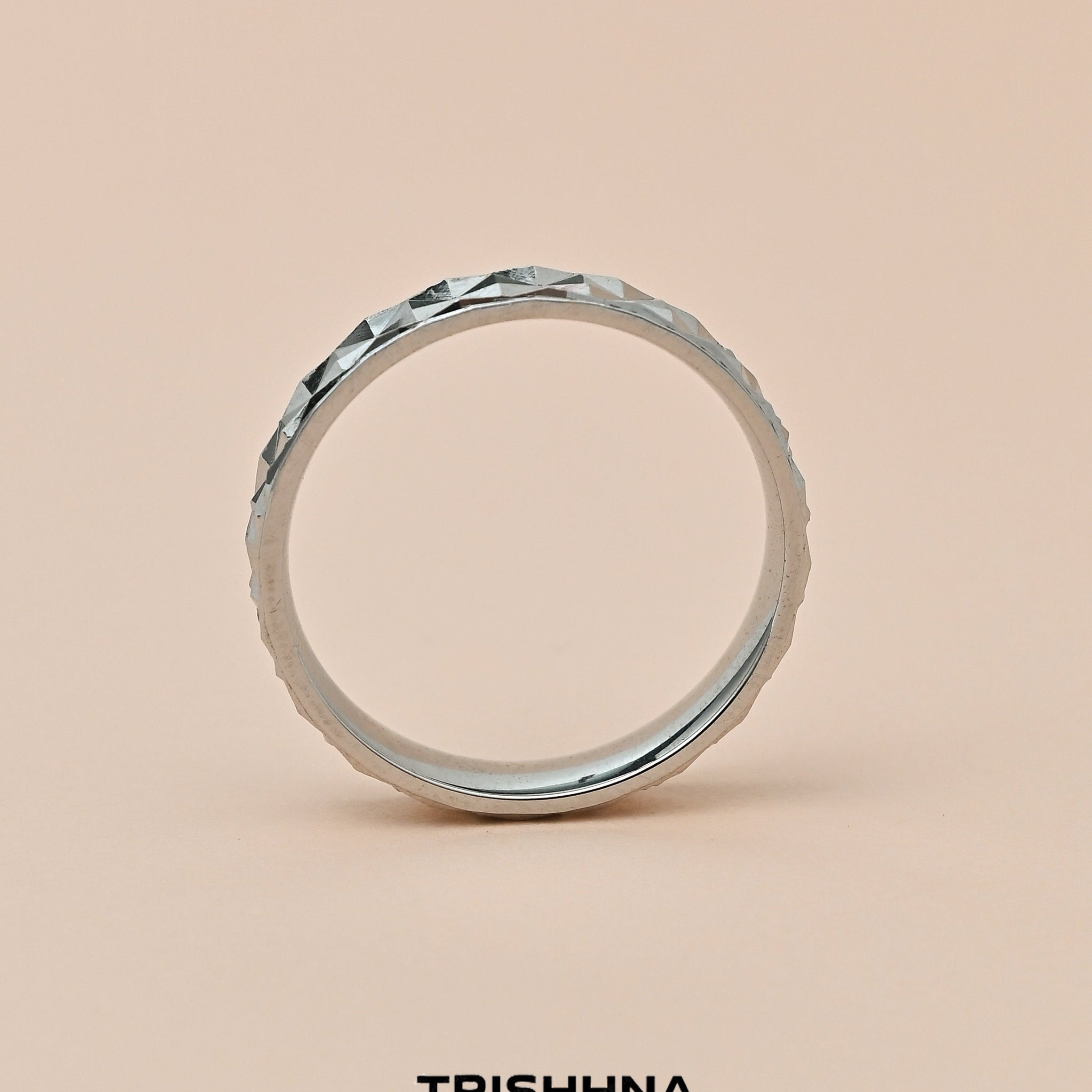 Silver ring with a textured band on a beige background, featuring the brand 'TRISHNHA'.