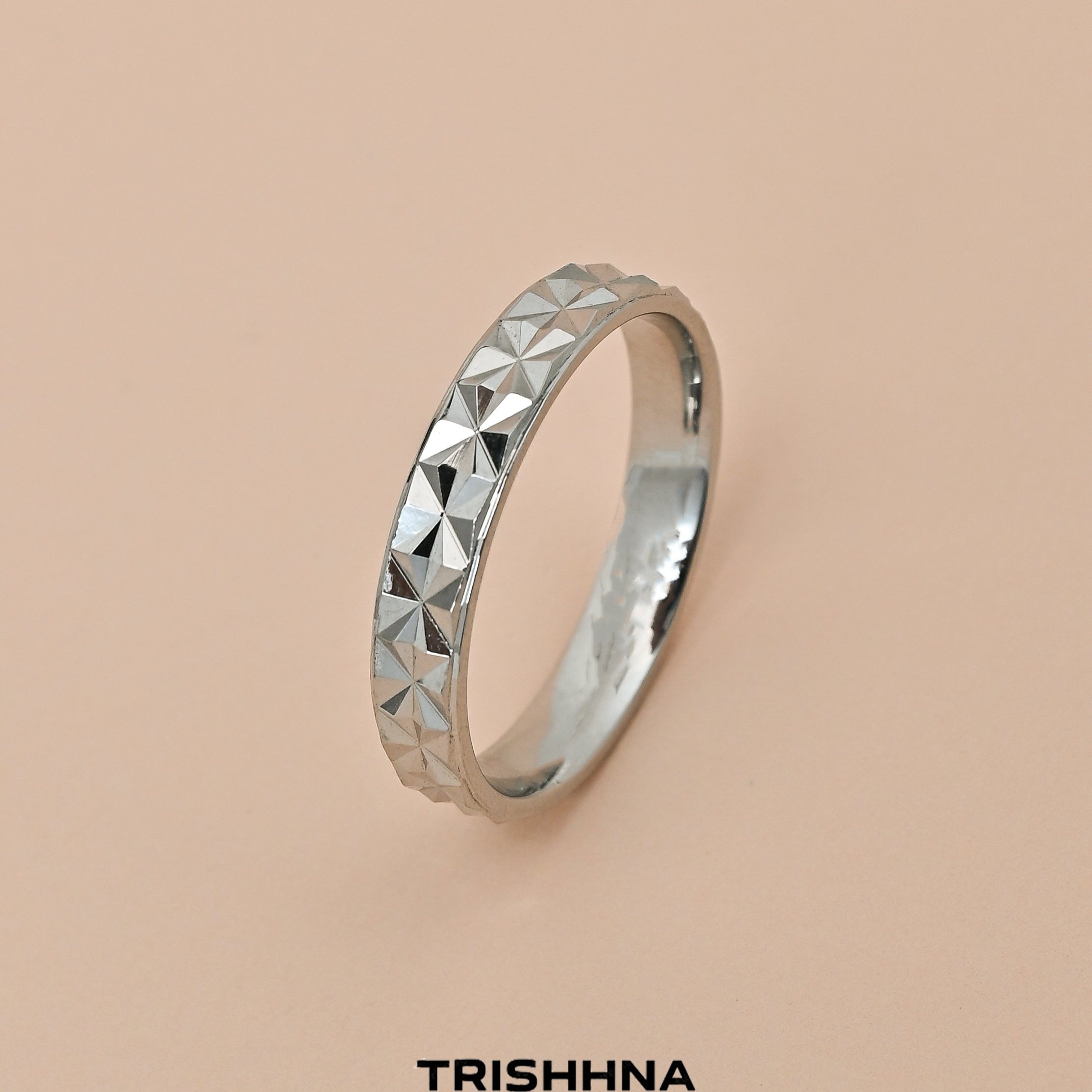 Silver ring with geometric design on a beige background, featuring the brand 'TRISHNNA'.