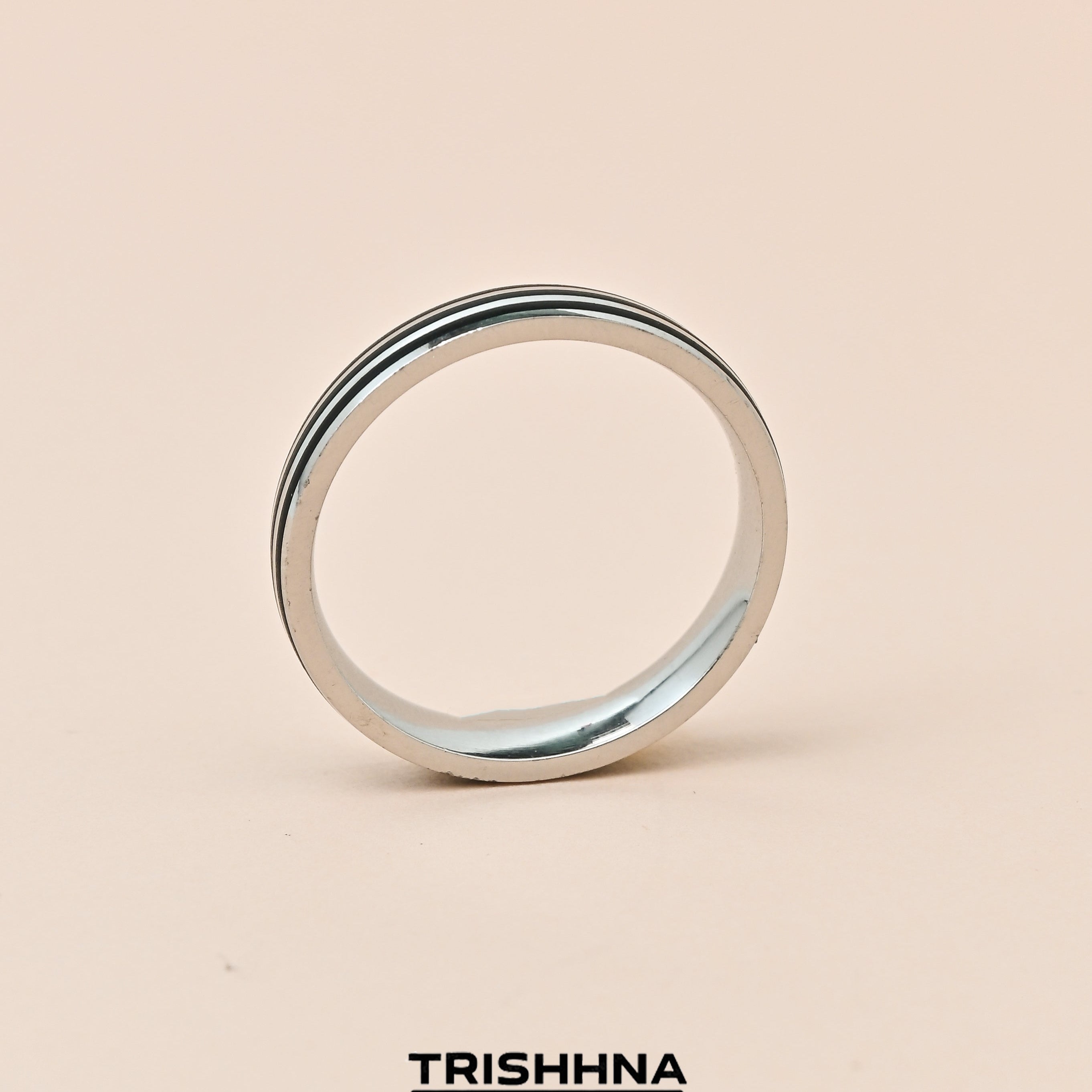 Silver ring on a beige background with 'TRISHNHA' branding.