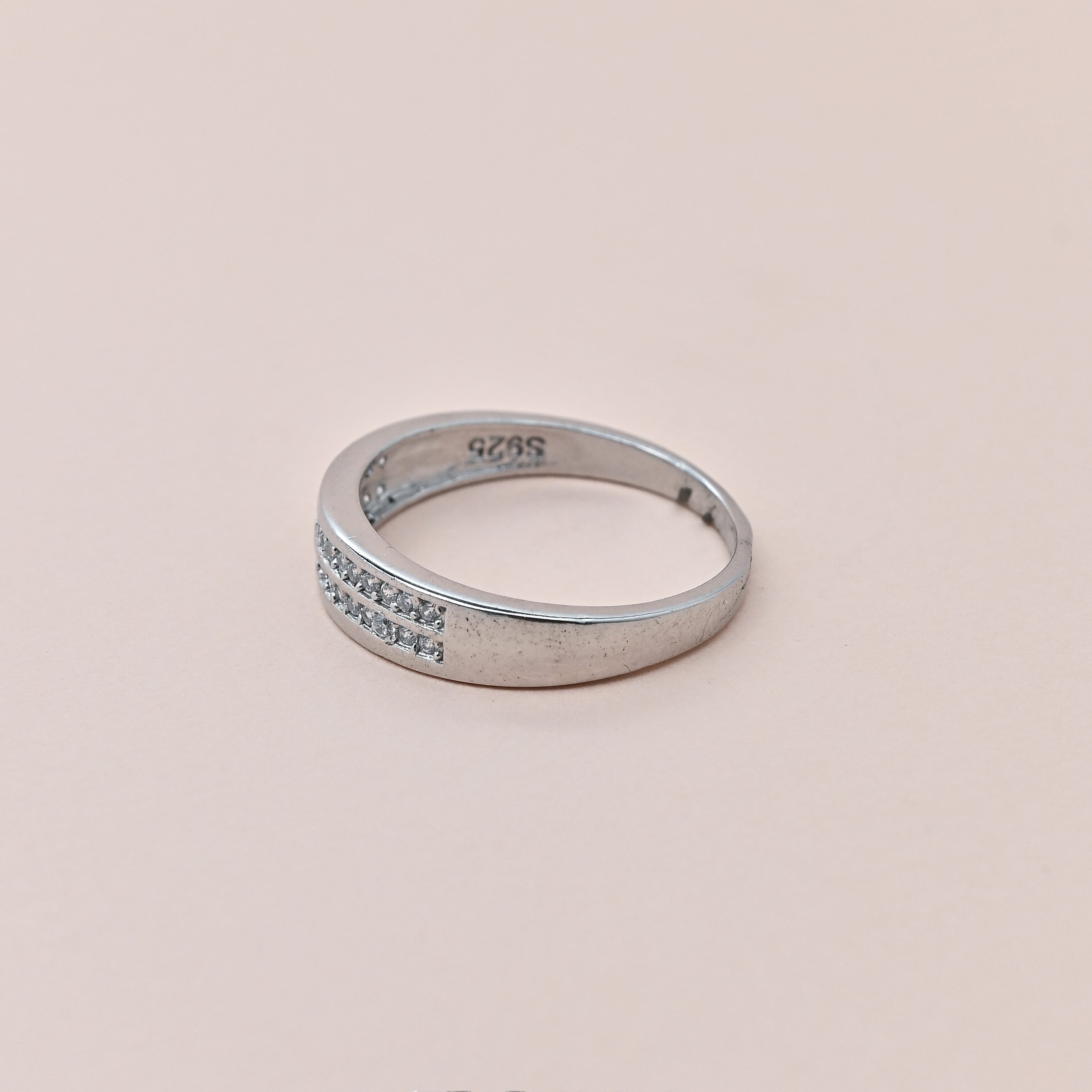 Silver ring with small diamonds on a beige background