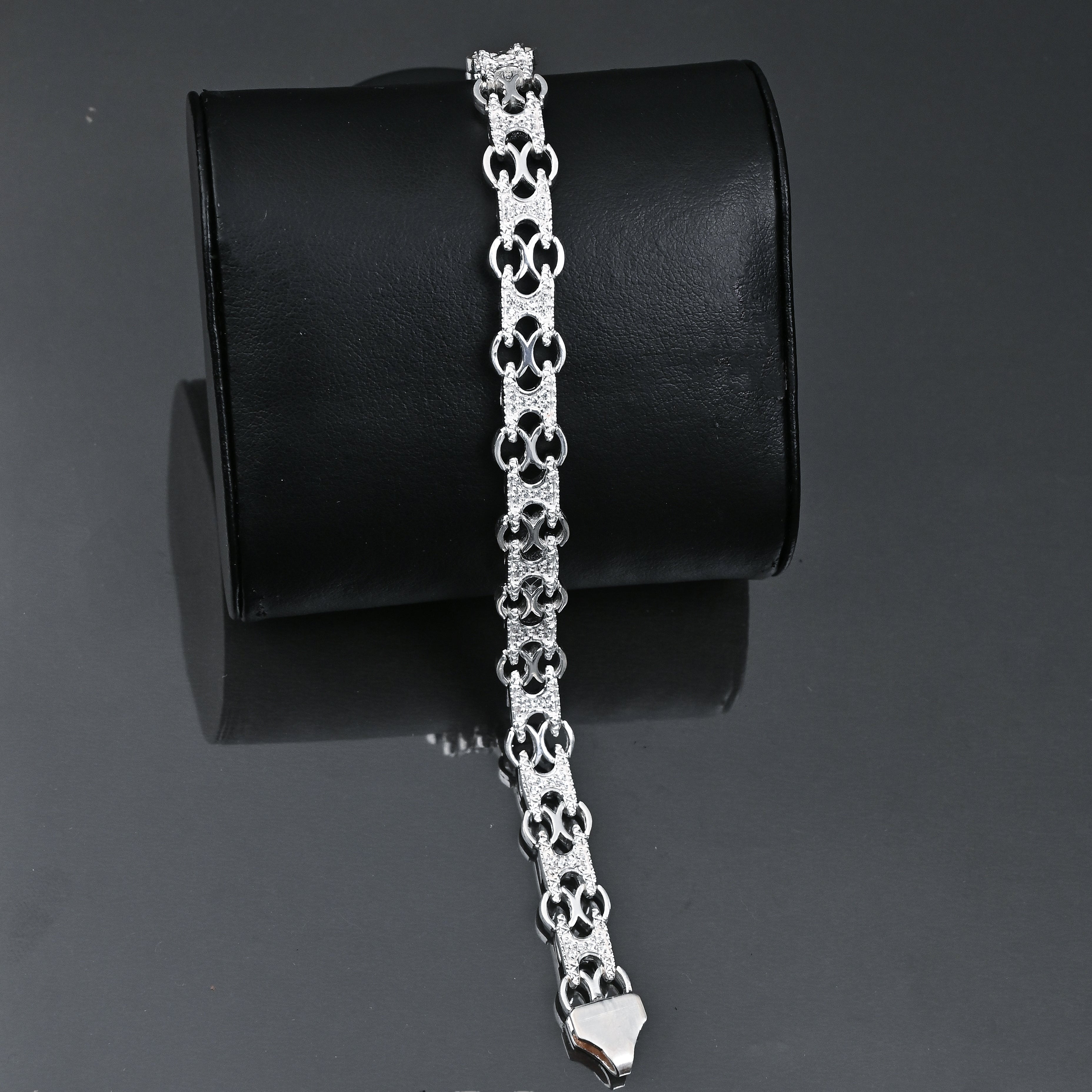 Silver bracelet on a black cylindrical stand with 'TRISHNHA' branding.