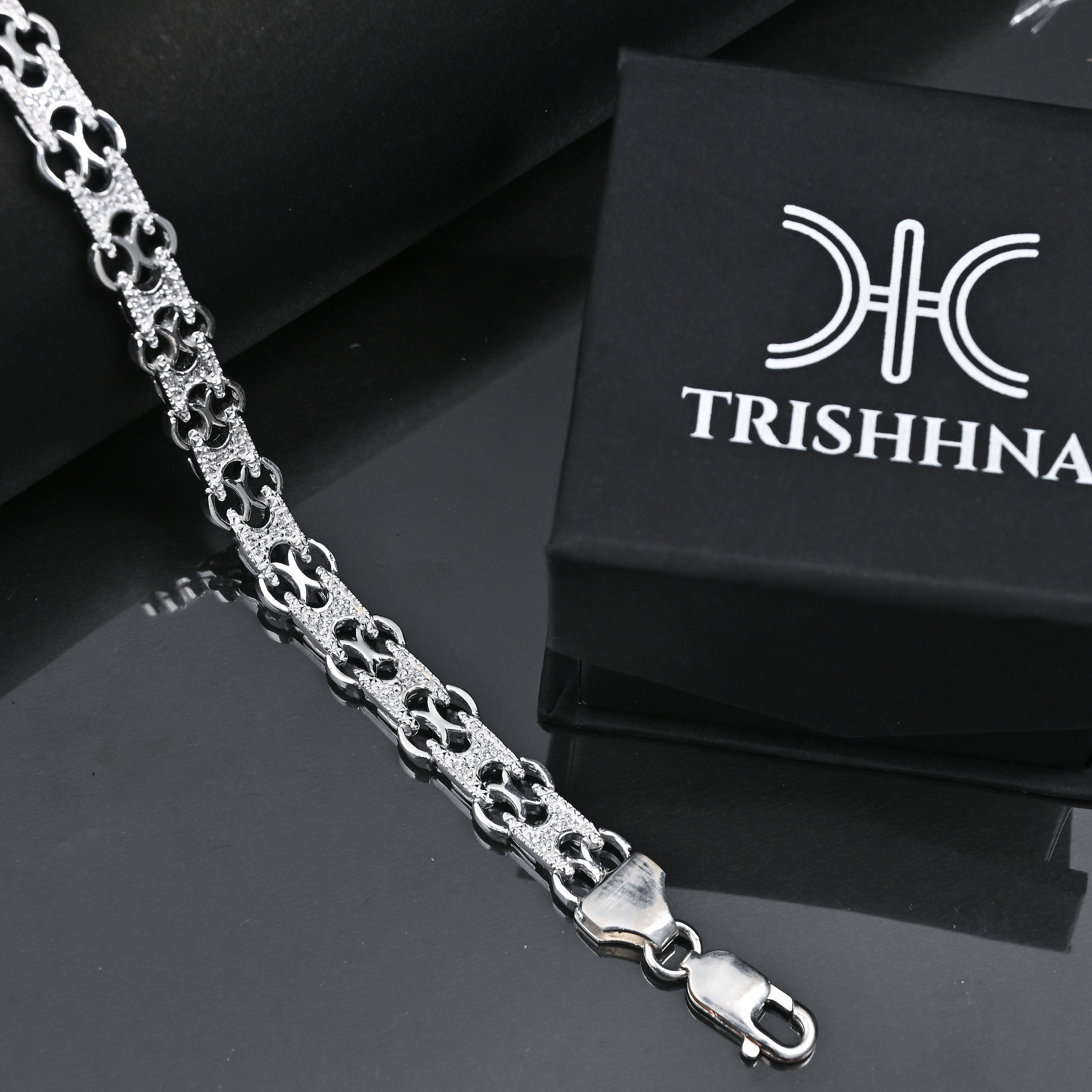 Silver chain bracelet with a black box featuring 'TRISHHNA' branding on a reflective surface.