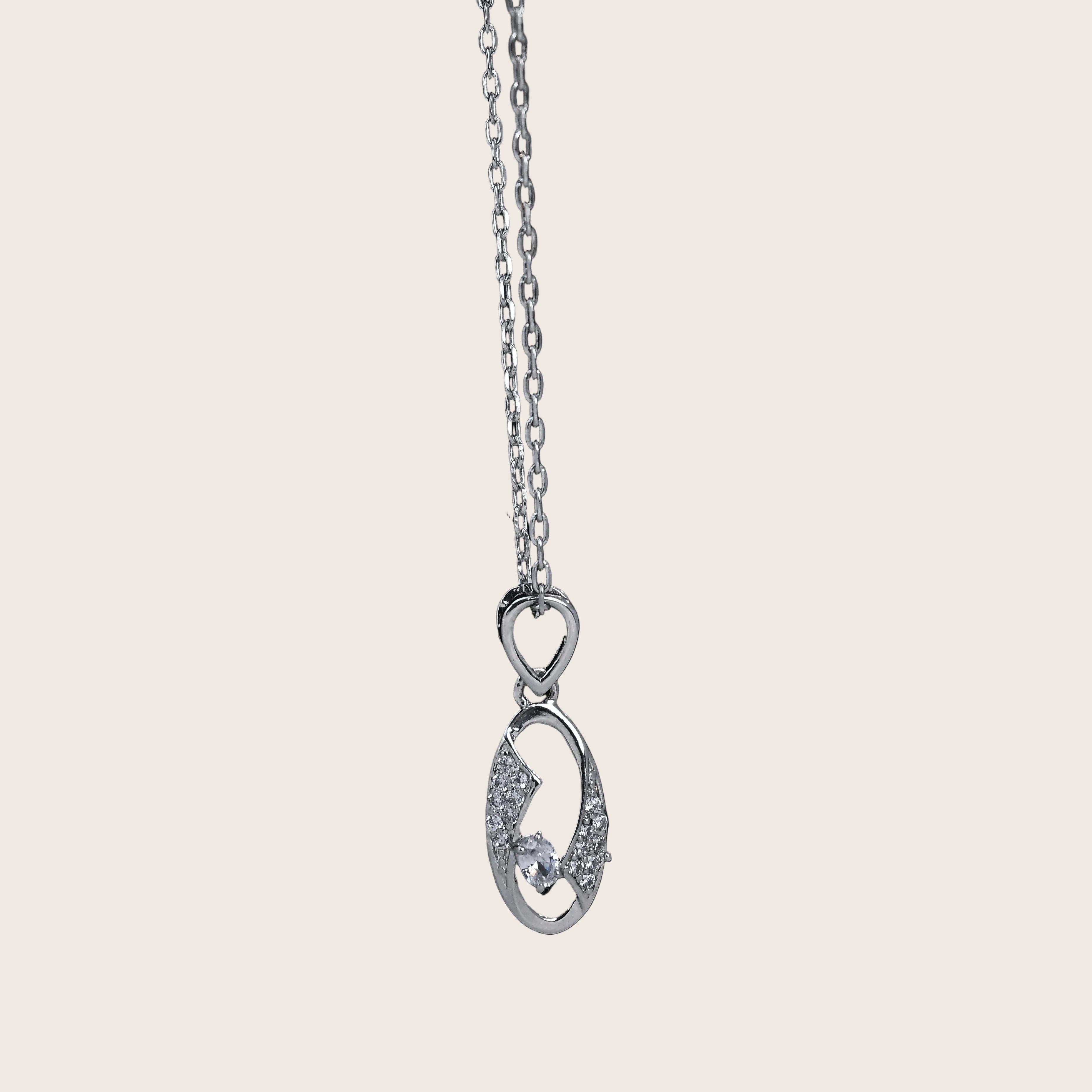 Silver necklace with a pendant on a black background, featuring the brand 'TRISHHNA'.