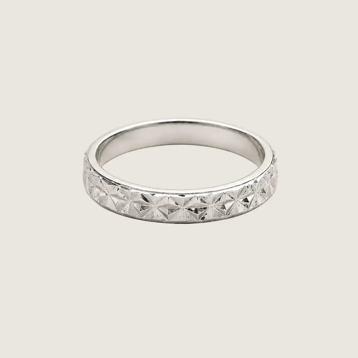 Silver ring with diamond-like stones on a light gray background