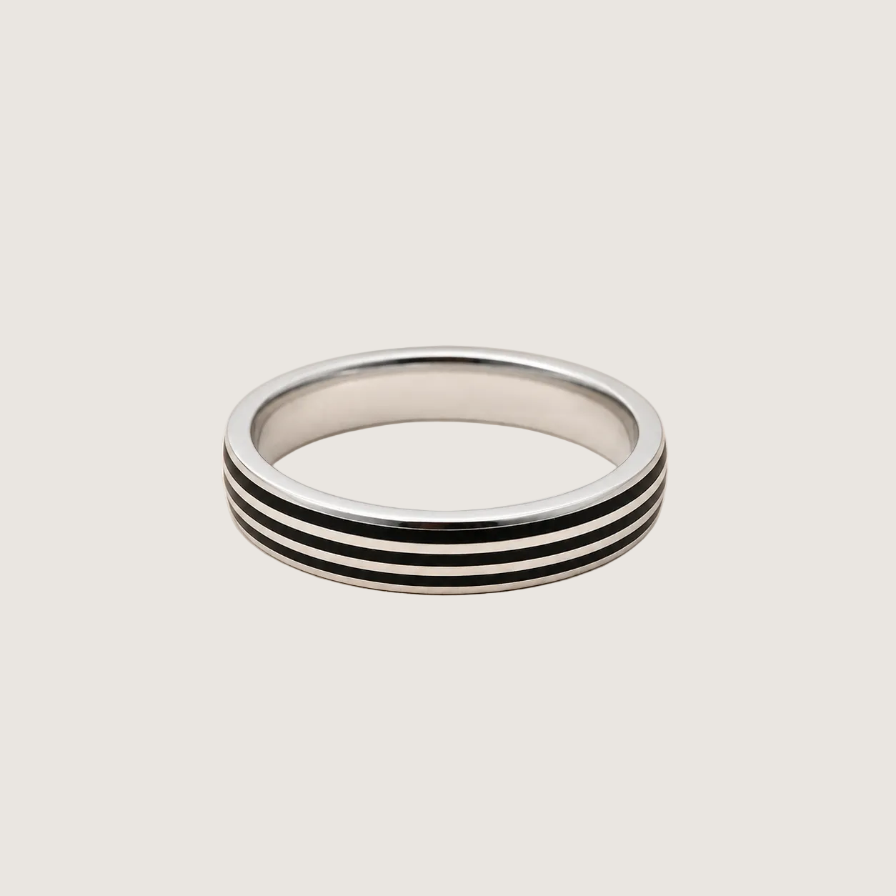 Silver ring with black stripes on a light beige background