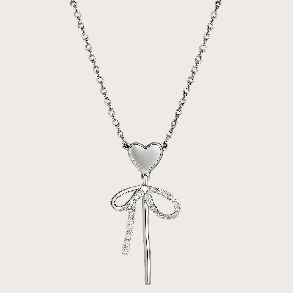 Silver necklace with a heart and bow pendant on a black background