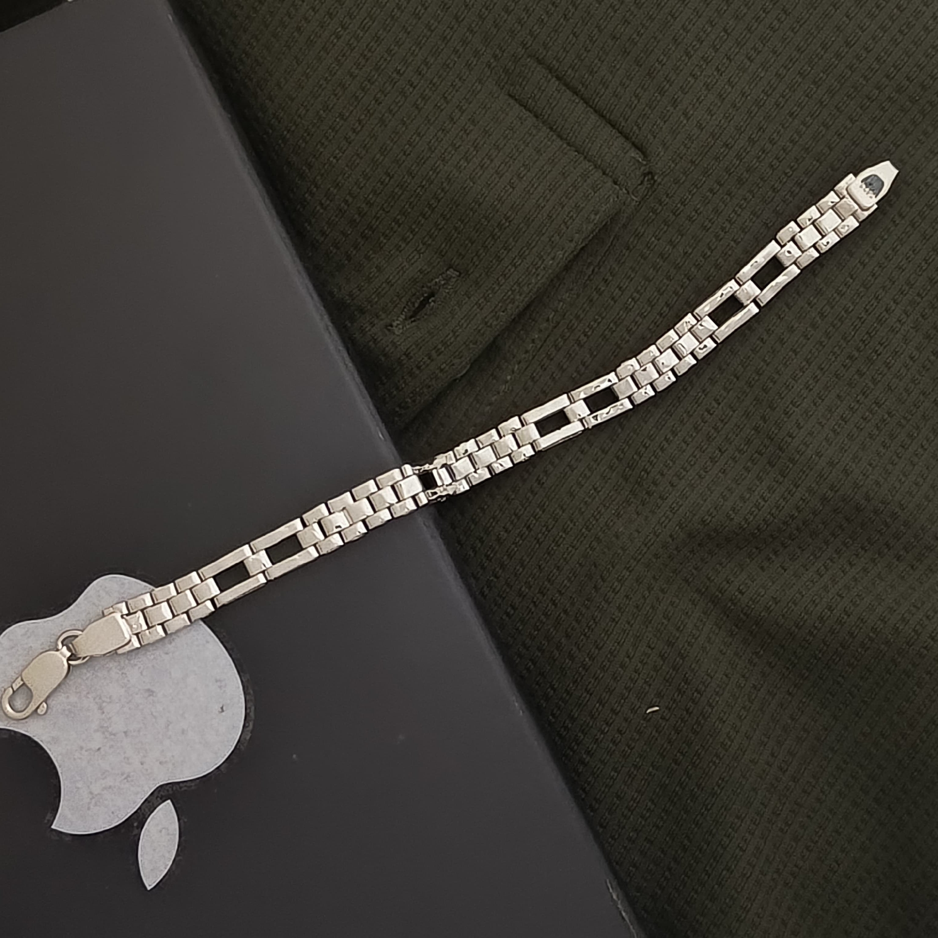 Silver bracelet on a dark surface with a green fabric background