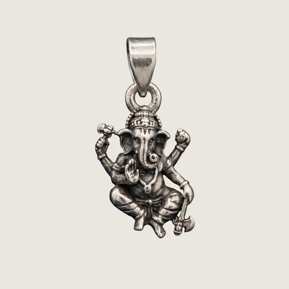 Silver pendant of a seated figure with outstretched arms on a beige background