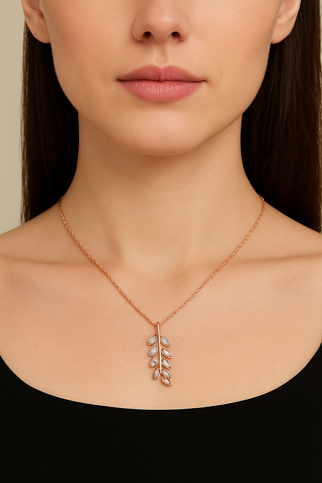 Rose gold necklace with leaf pendant on a model against a neutral background