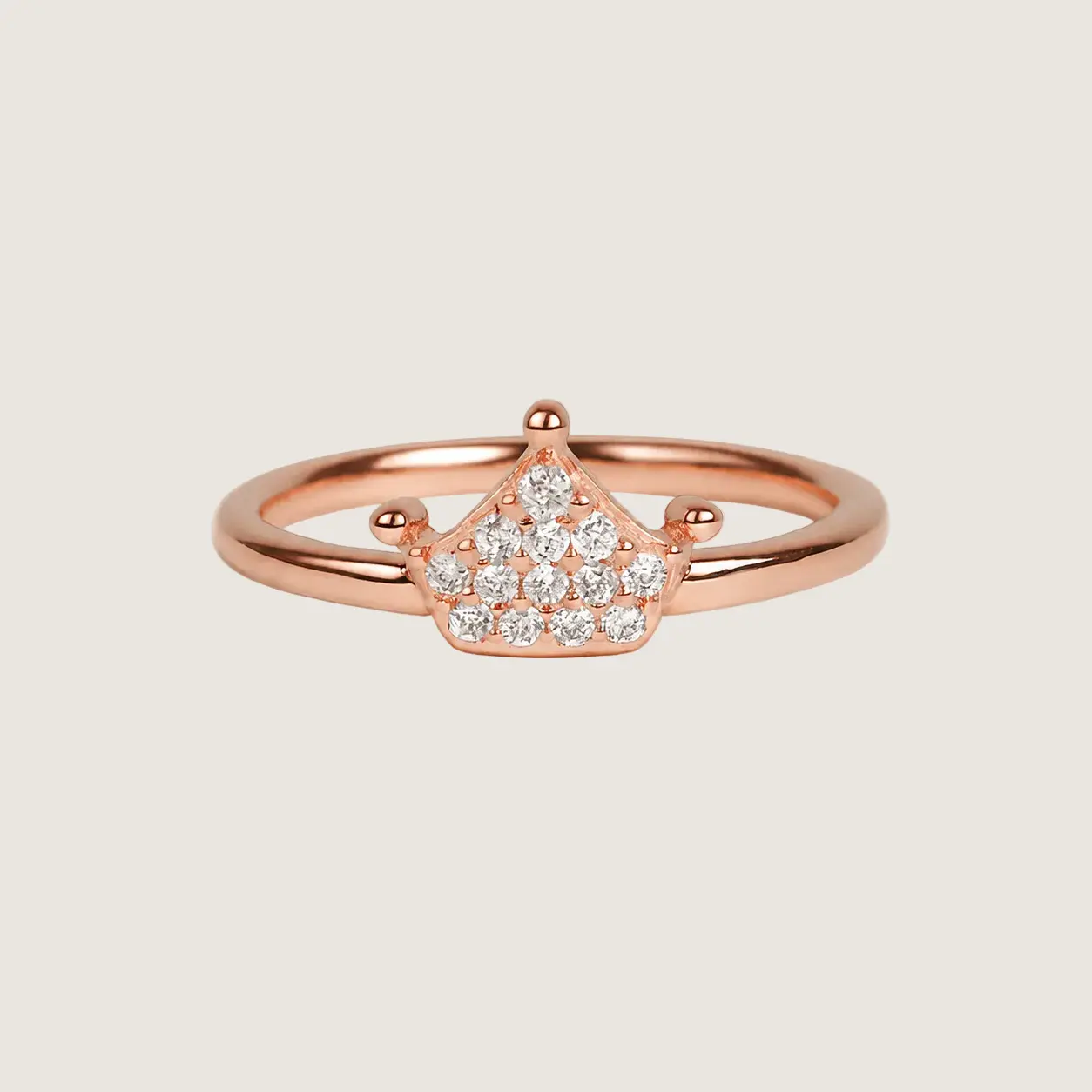Rose gold ring with diamond accents on a beige background