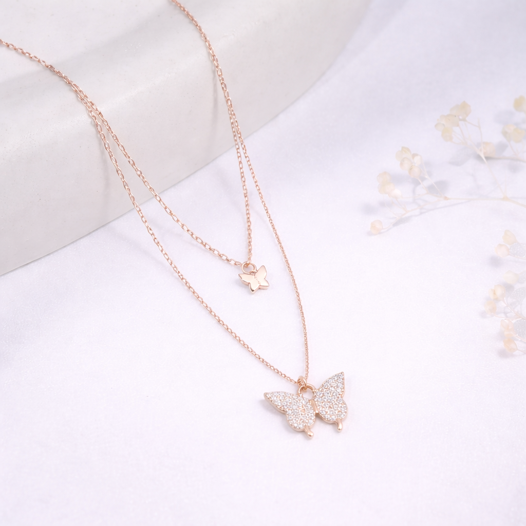 Rose gold butterfly necklace on a white background