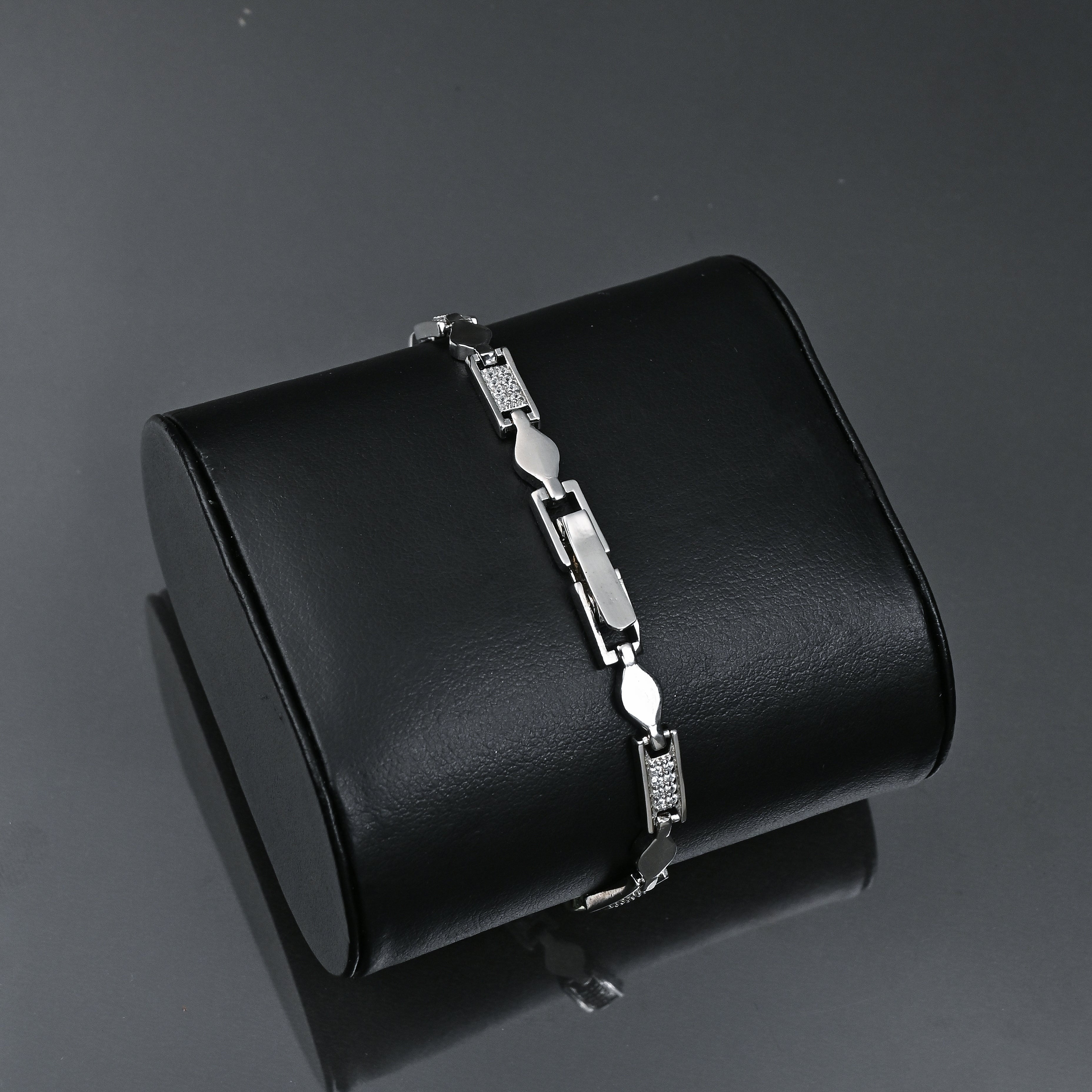 Silver bracelet on a black cylindrical box with 'TRISHNHA' branding against a dark background