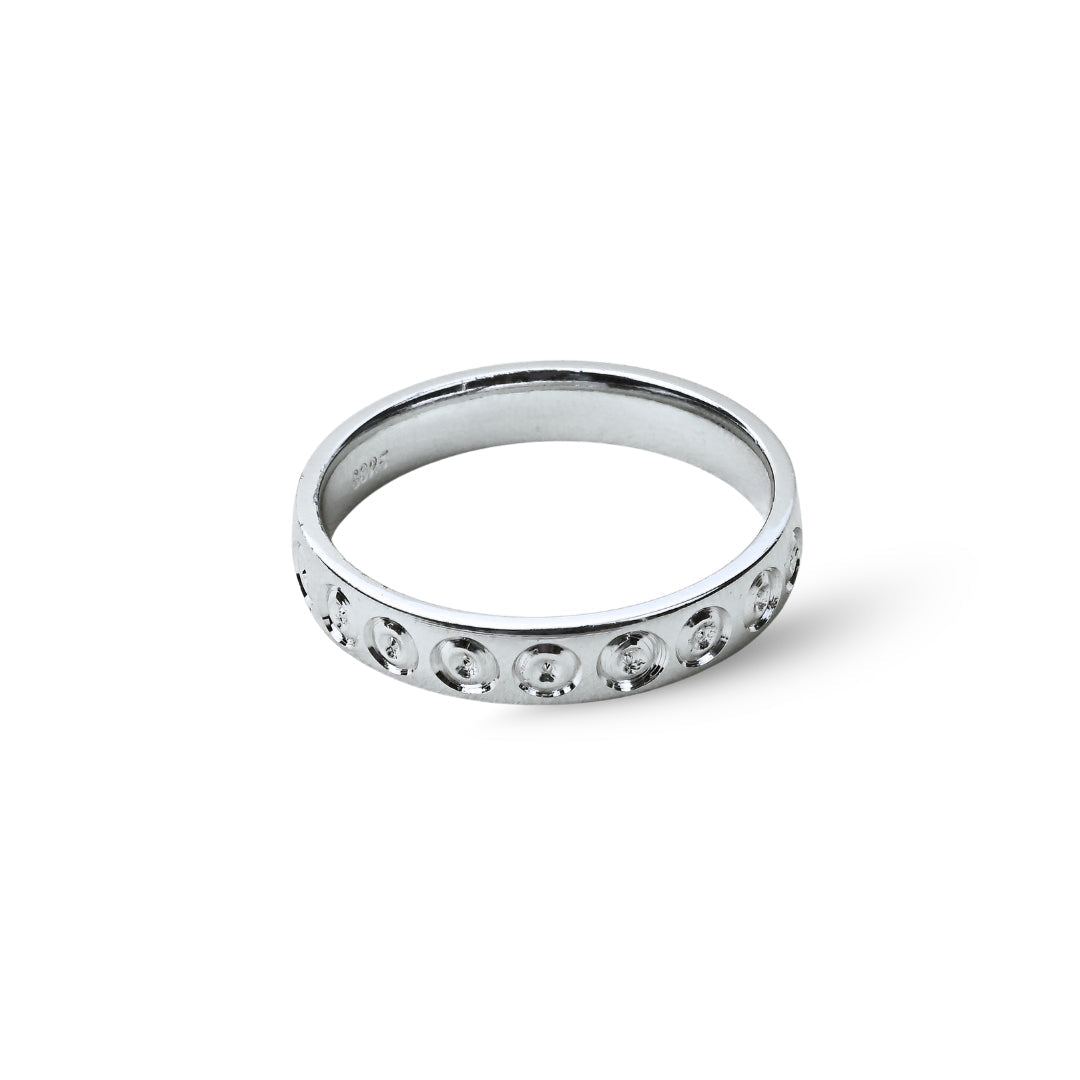 Silver ring with small stones on a white background, branded 'TRISHNNA'.