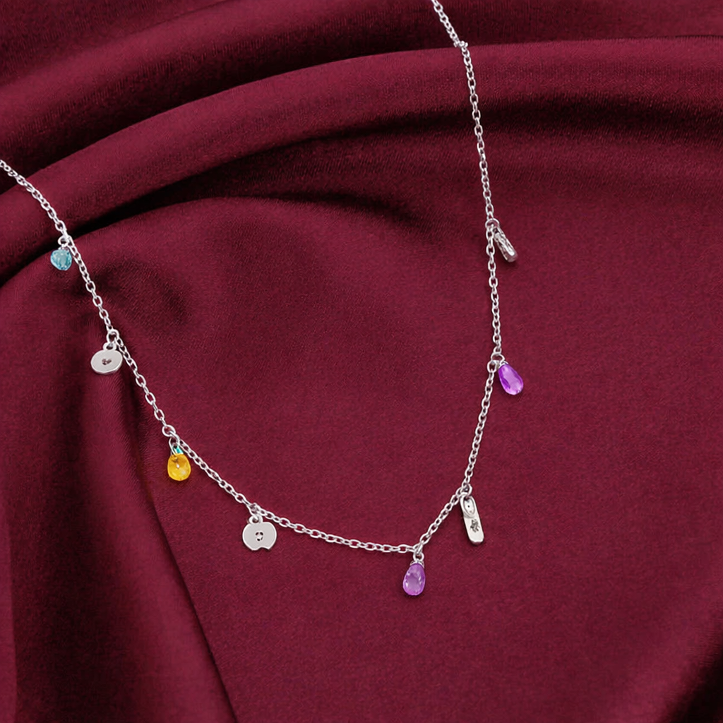Silver necklace with colorful charms on a maroon fabric background