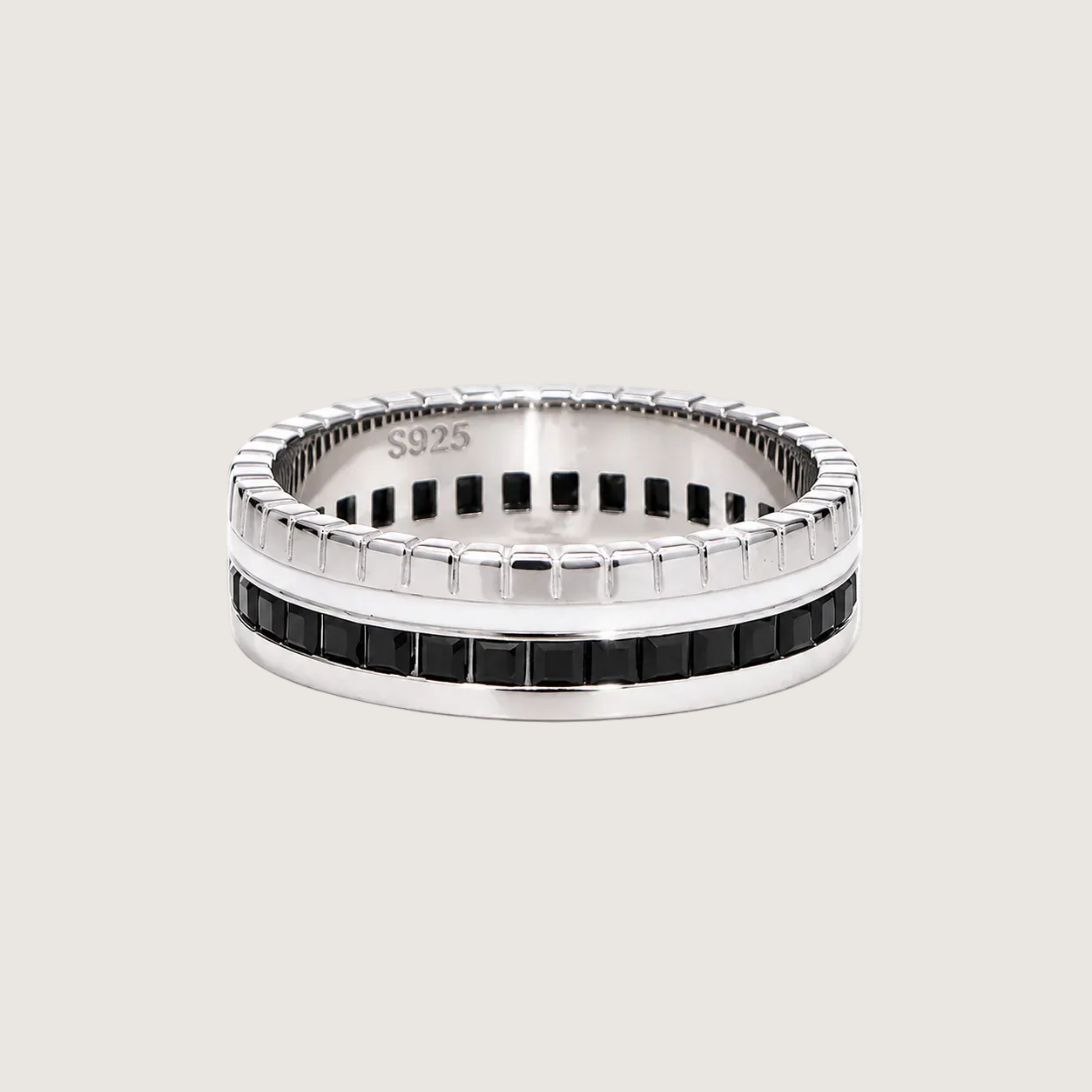 Silver ring with black accents on a beige background