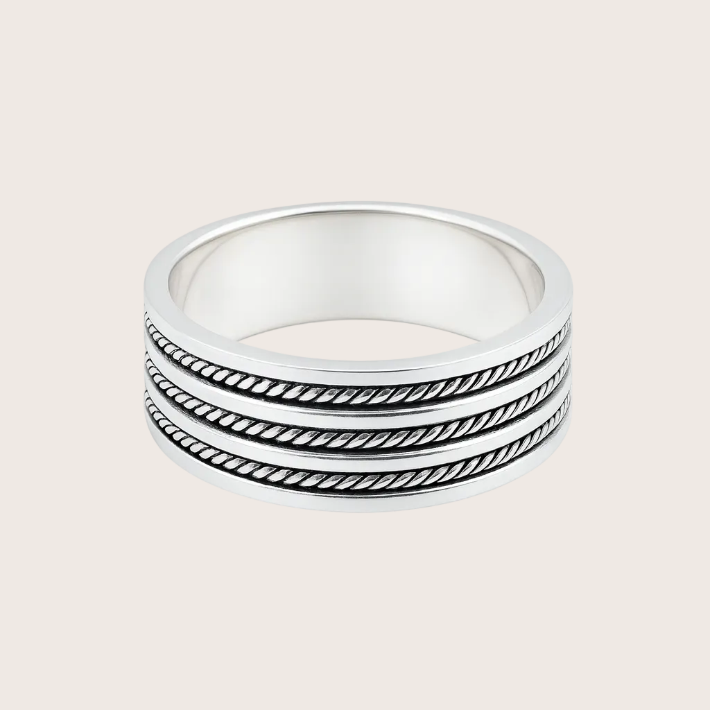 Stack of three silver rings with textured band design on a white background