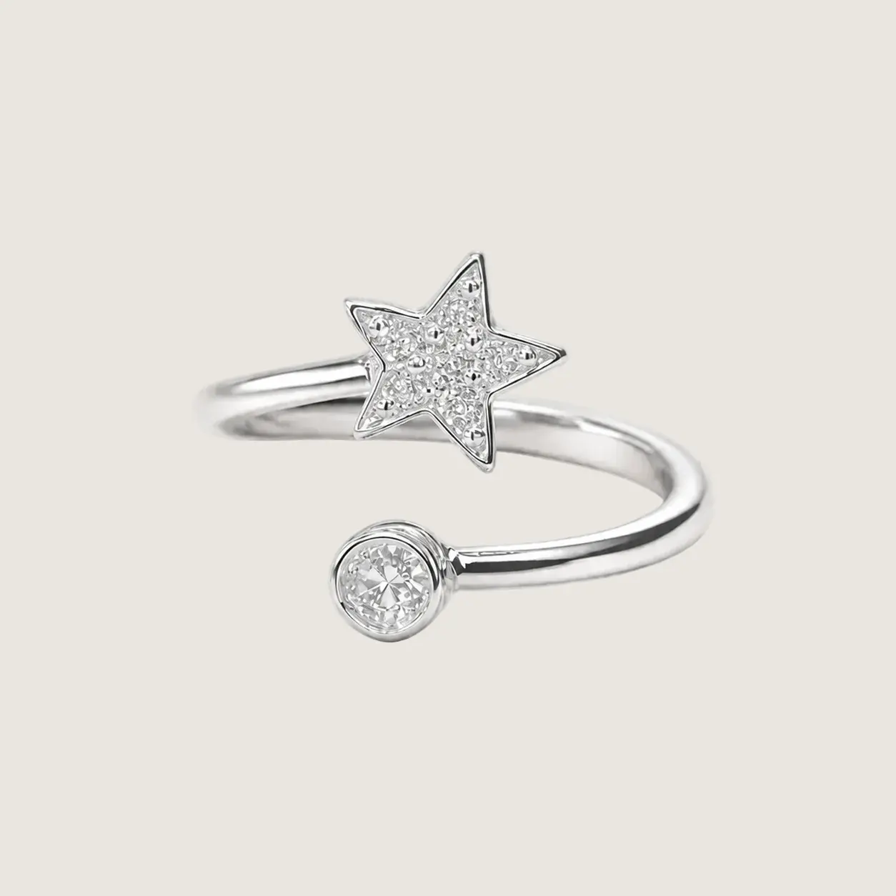 Silver ring with star and round diamond design on a light beige background