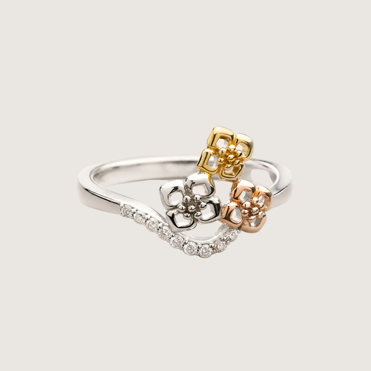 Three gold rings with floral designs on a light beige background