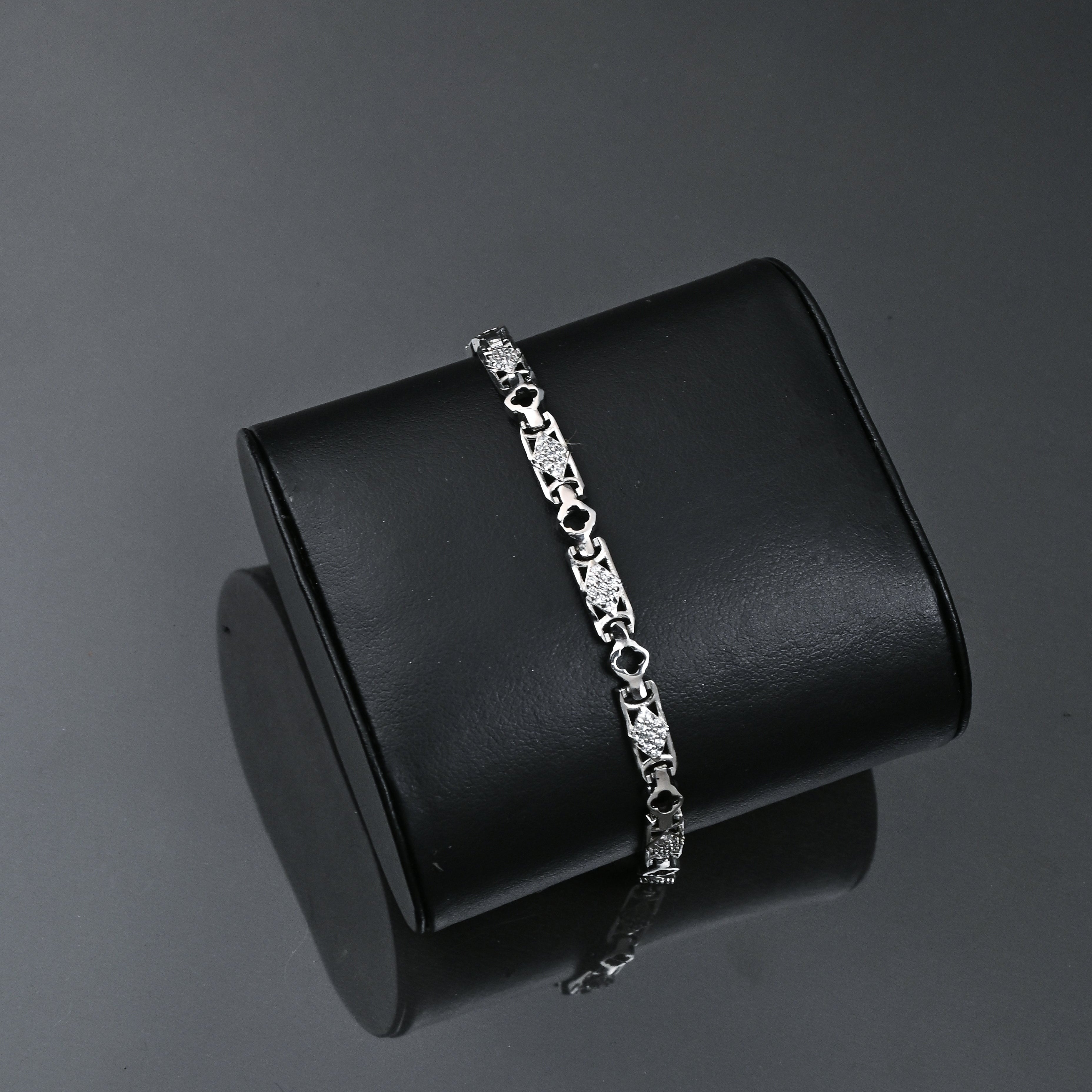Silver bracelet on a black stand with 'TRISHNHA' branding on a dark background