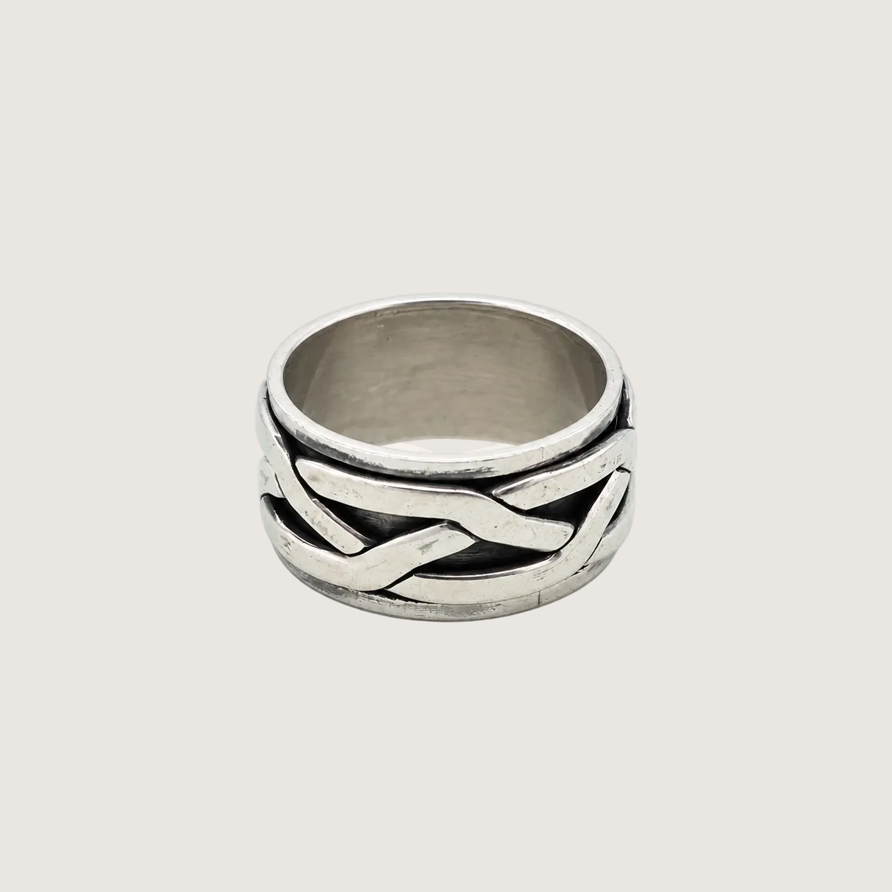 Silver ring with braided design on a light beige background
