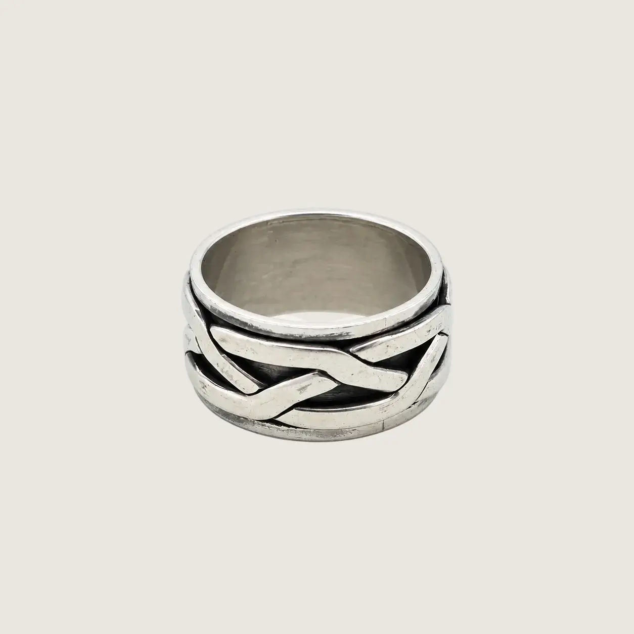 Silver ring with braided design on a light beige background