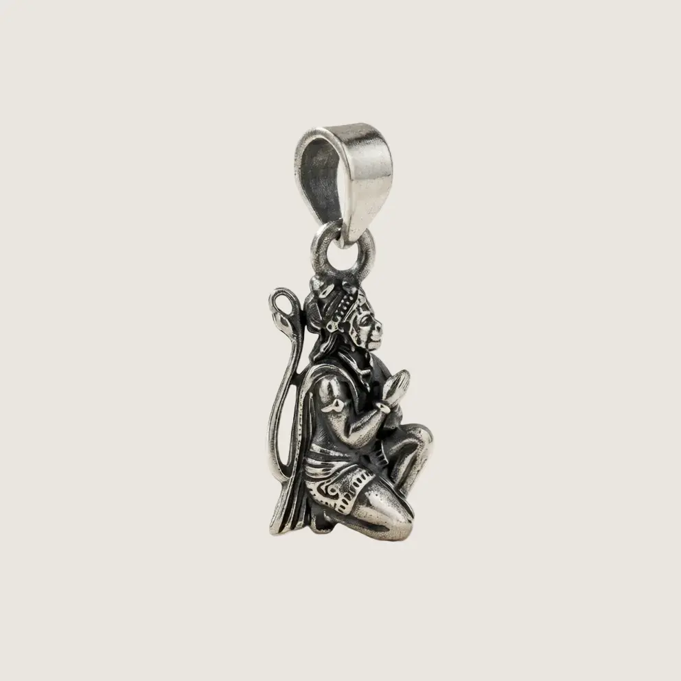 Silver pendant of a seated figure on a light gray background