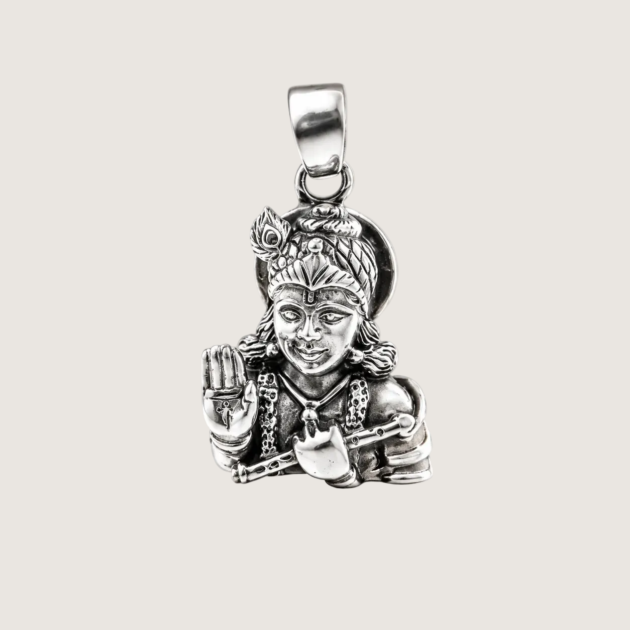 Silver pendant of a deity on a beige background