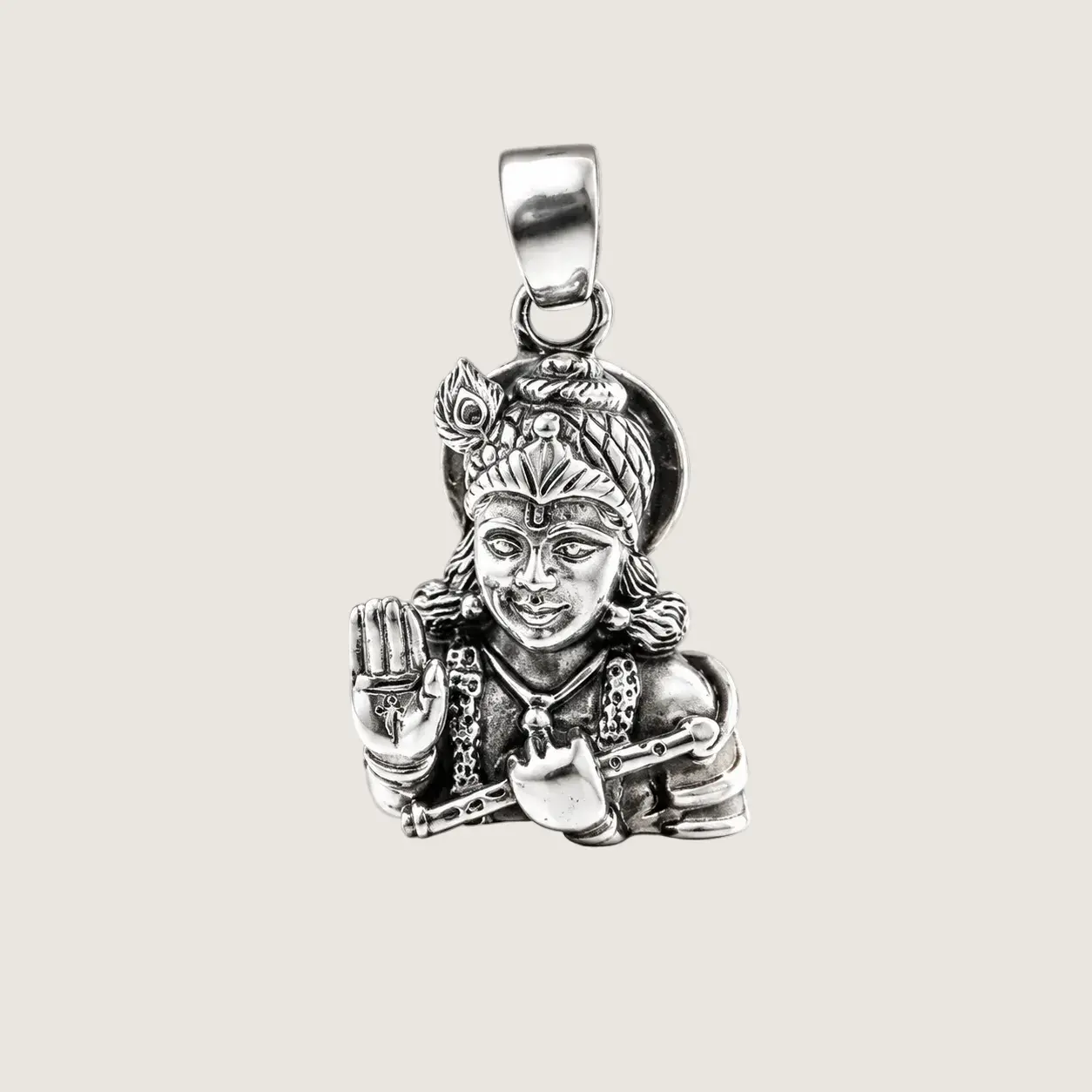 Silver pendant of a deity on a beige background