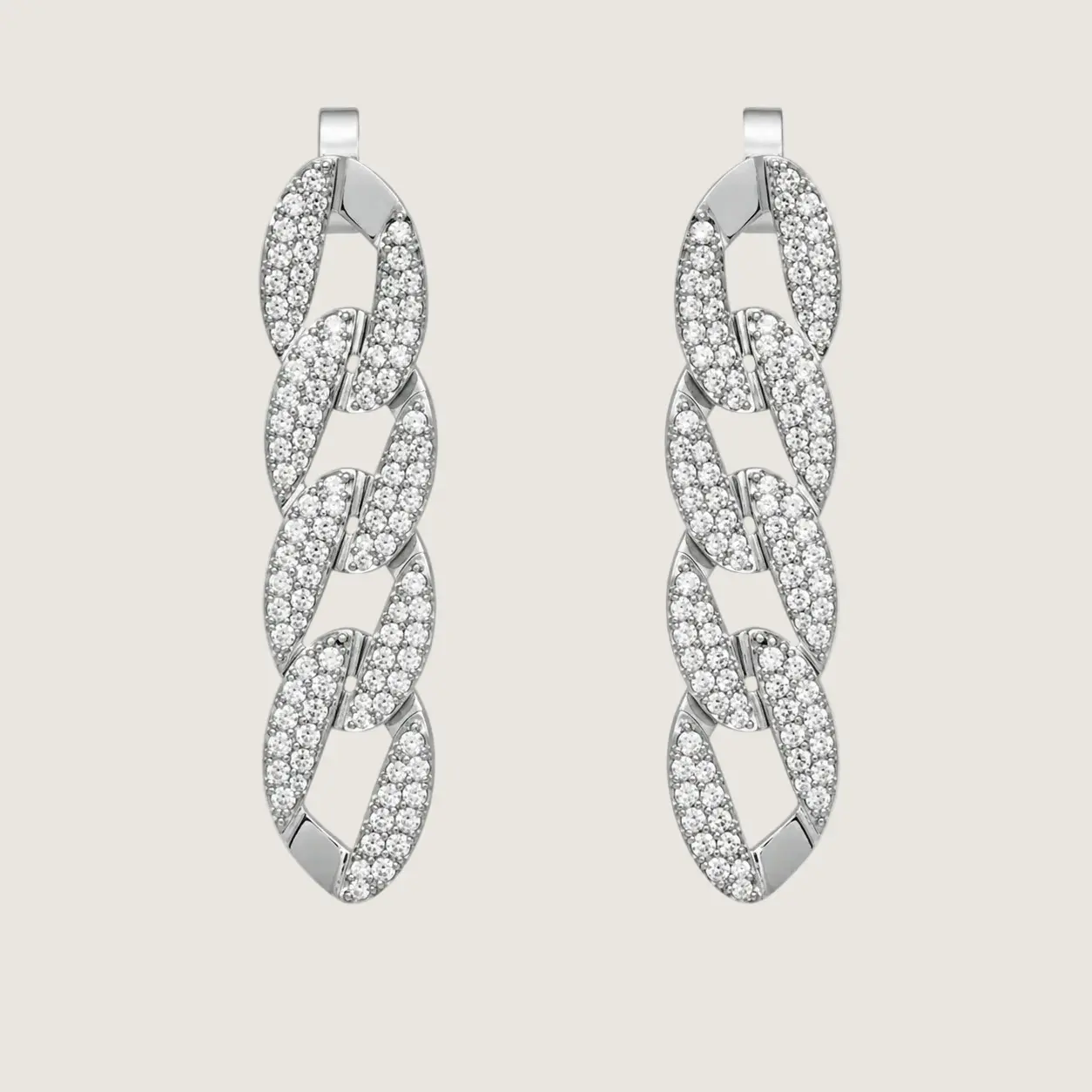 Pair of silver earrings with diamond-like stones on a light gray background
