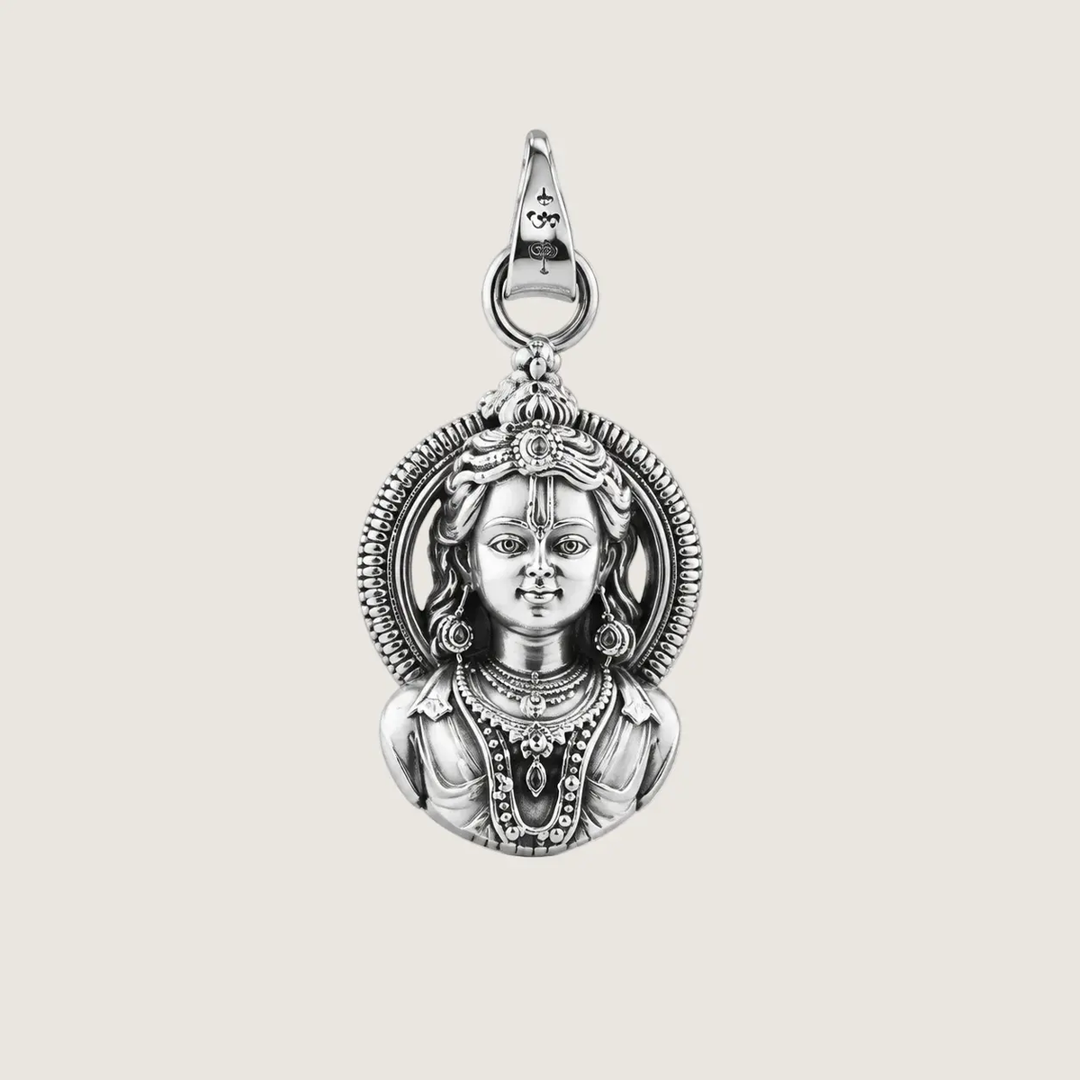 Silver pendant with intricate design on a beige background