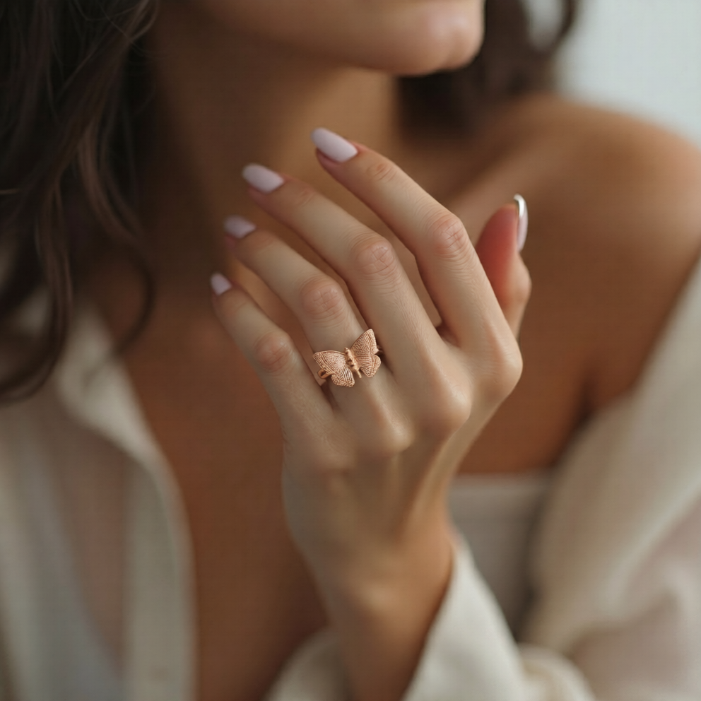 Close-up of a hand wearing a butterfly-shaped ring with a soft focus background