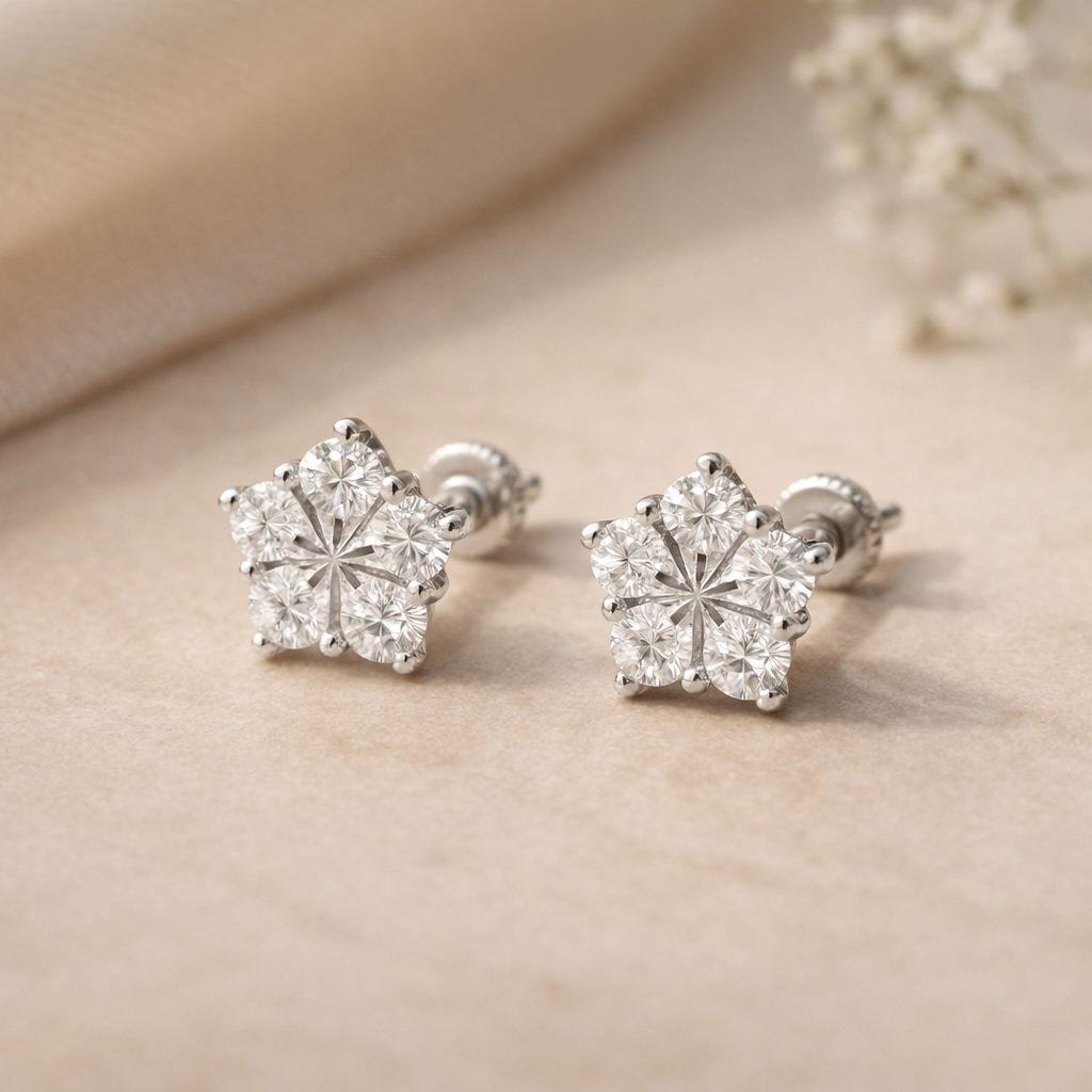 Pair of silver earrings with diamond-like stones on a beige surface.