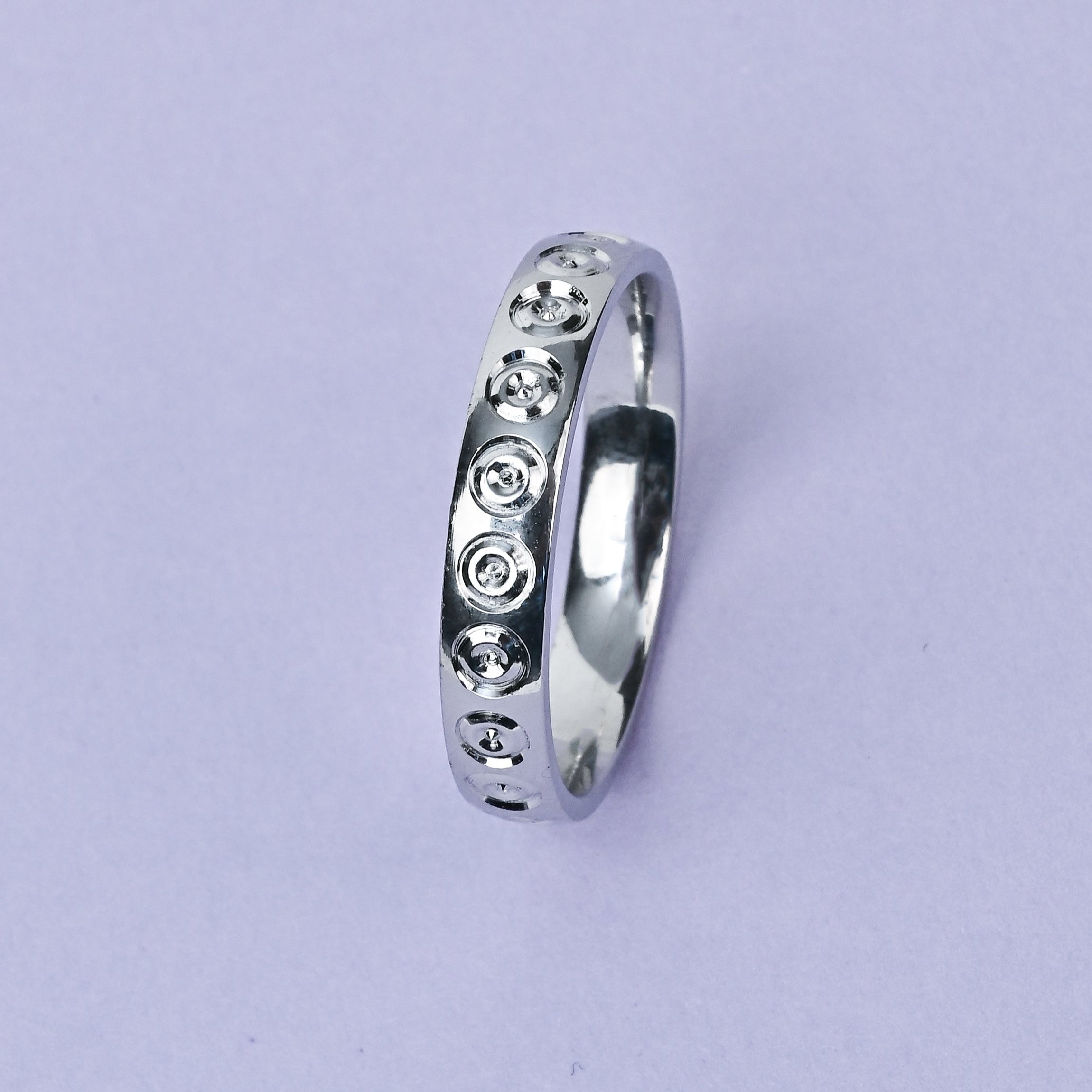 Silver ring with embedded stones on a light purple background, featuring the brand 'TRISHNHA'.