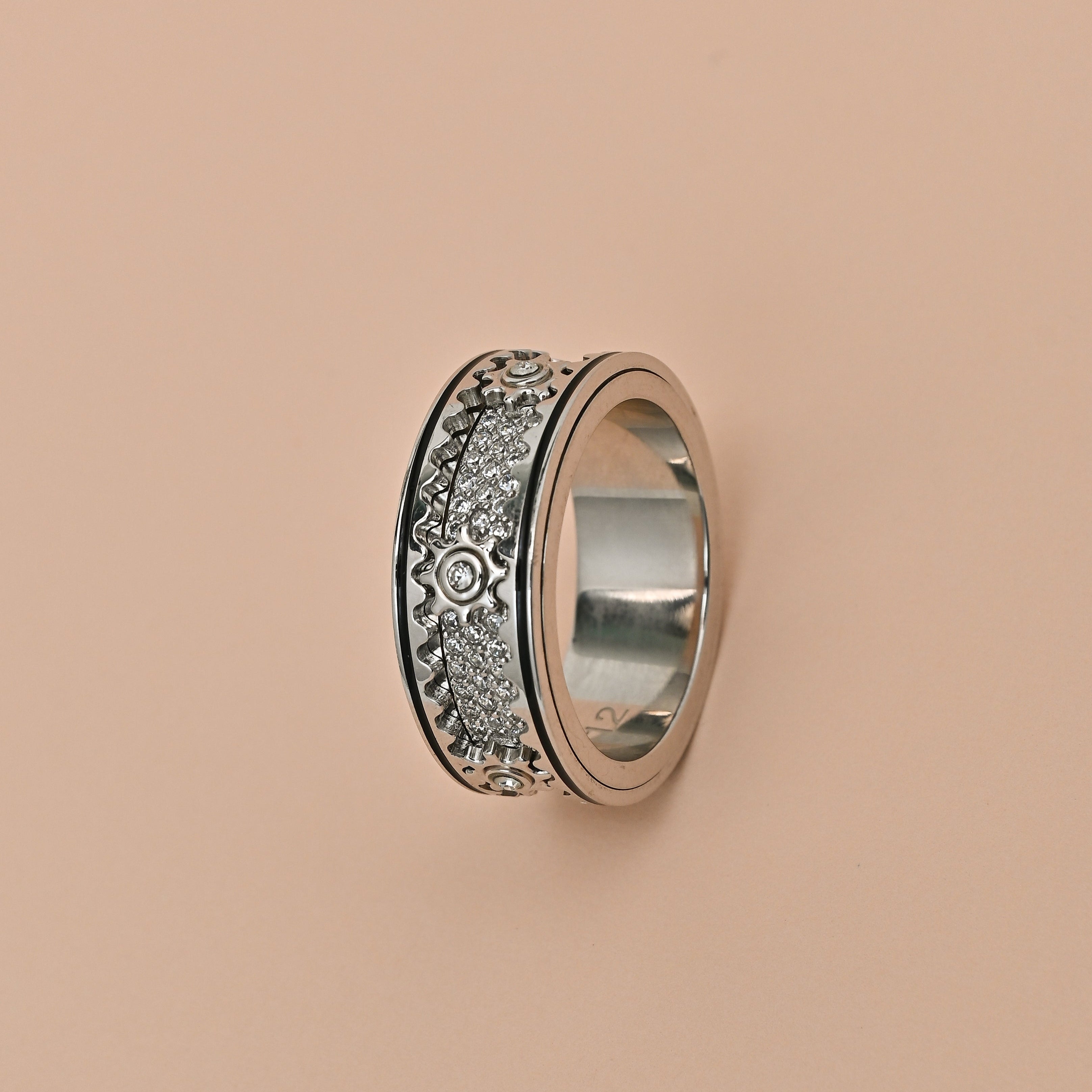 Silver ring with intricate design on a beige background, featuring the brand 'TRISHNHA'.