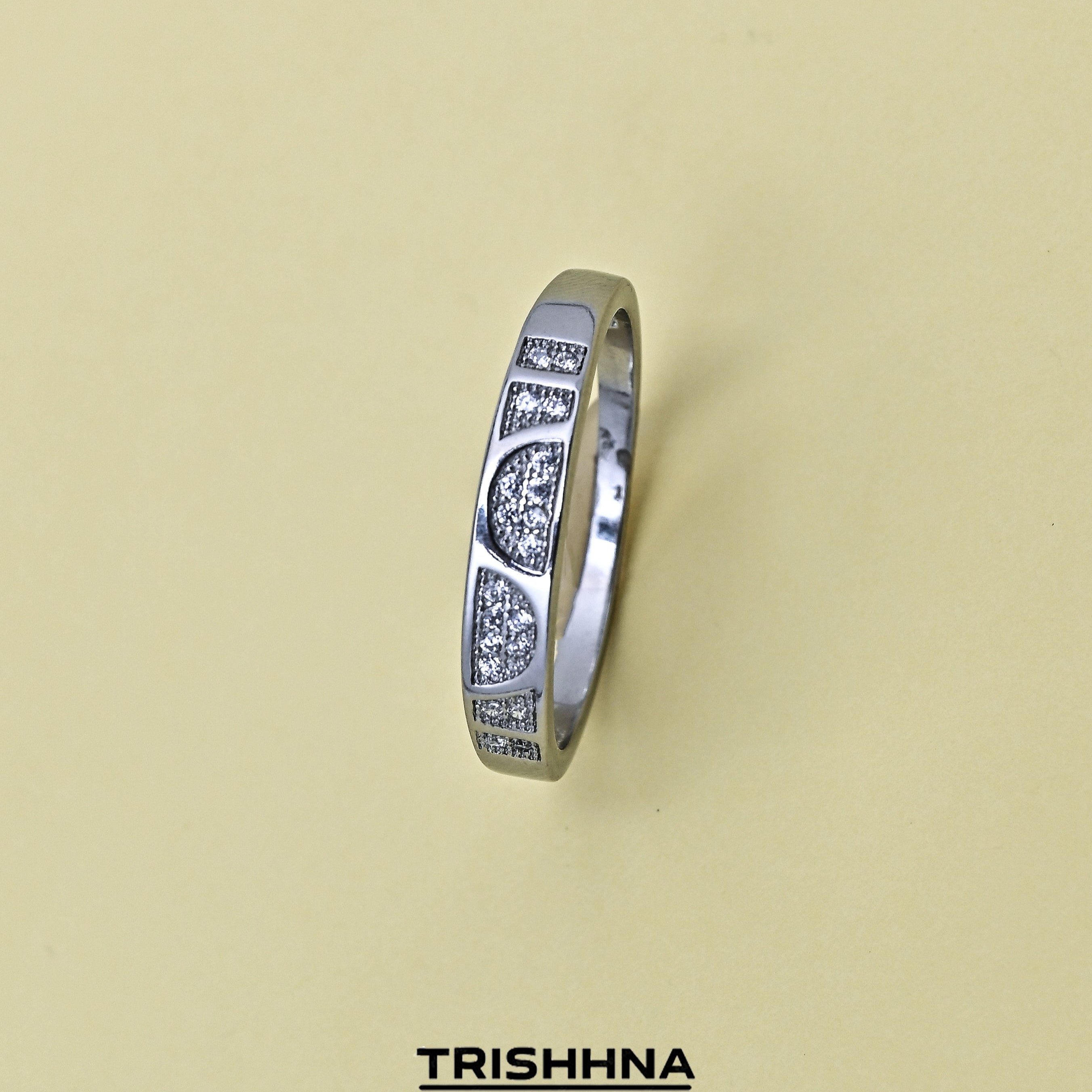 Silver ring with engraved design on a beige background, featuring the brand 'TRISHNHA'.