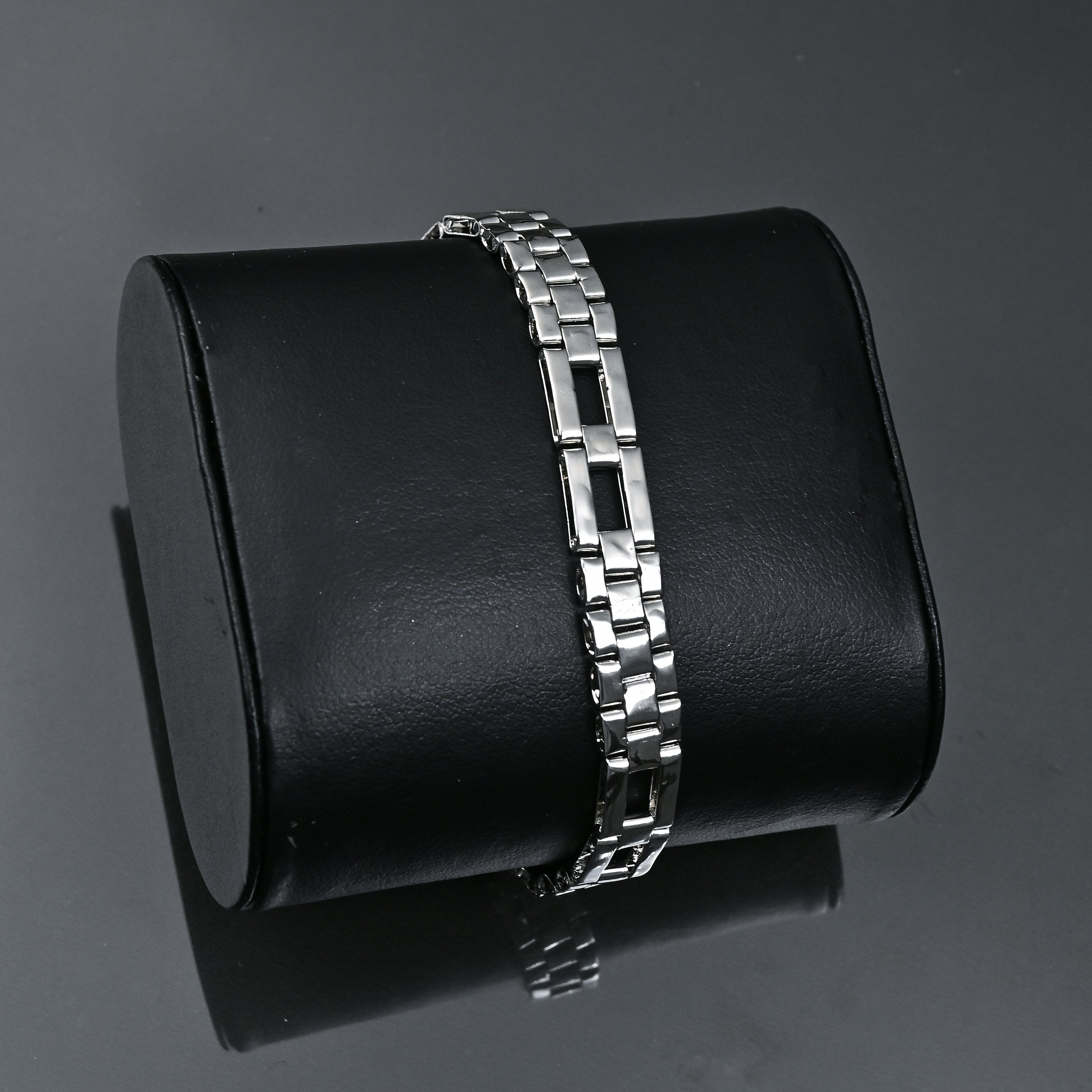 Silver bracelet on a black cylindrical stand with 'TRISHNHA' branding on a dark background