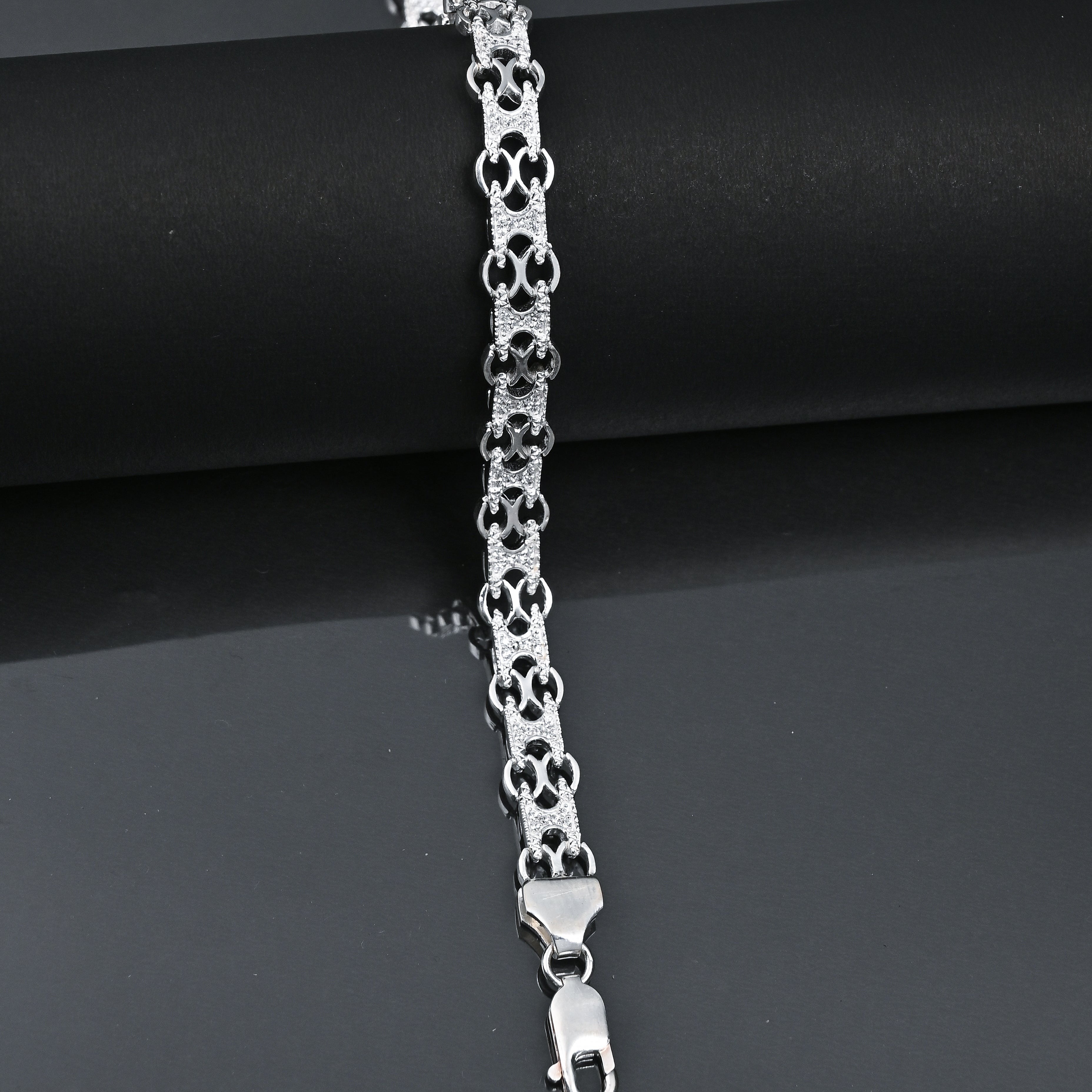 Silver bracelet with intricate design on a dark surface, featuring the brand 'TRISHNNA'.