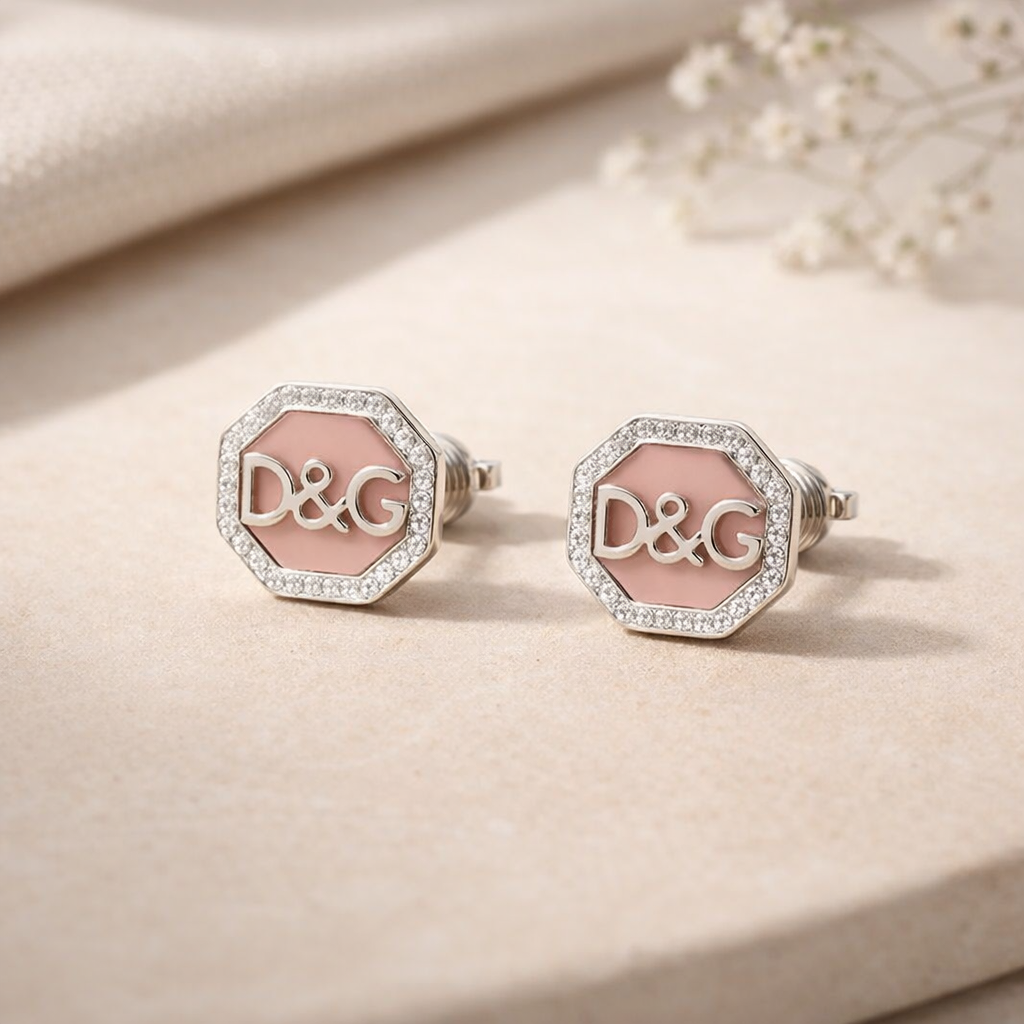 Pair of earrings with pink center and 'D&G' logo on a beige background