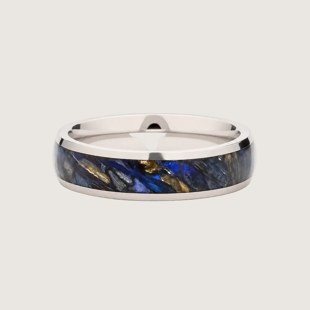 Silver ring with blue and gold inlay on a light background