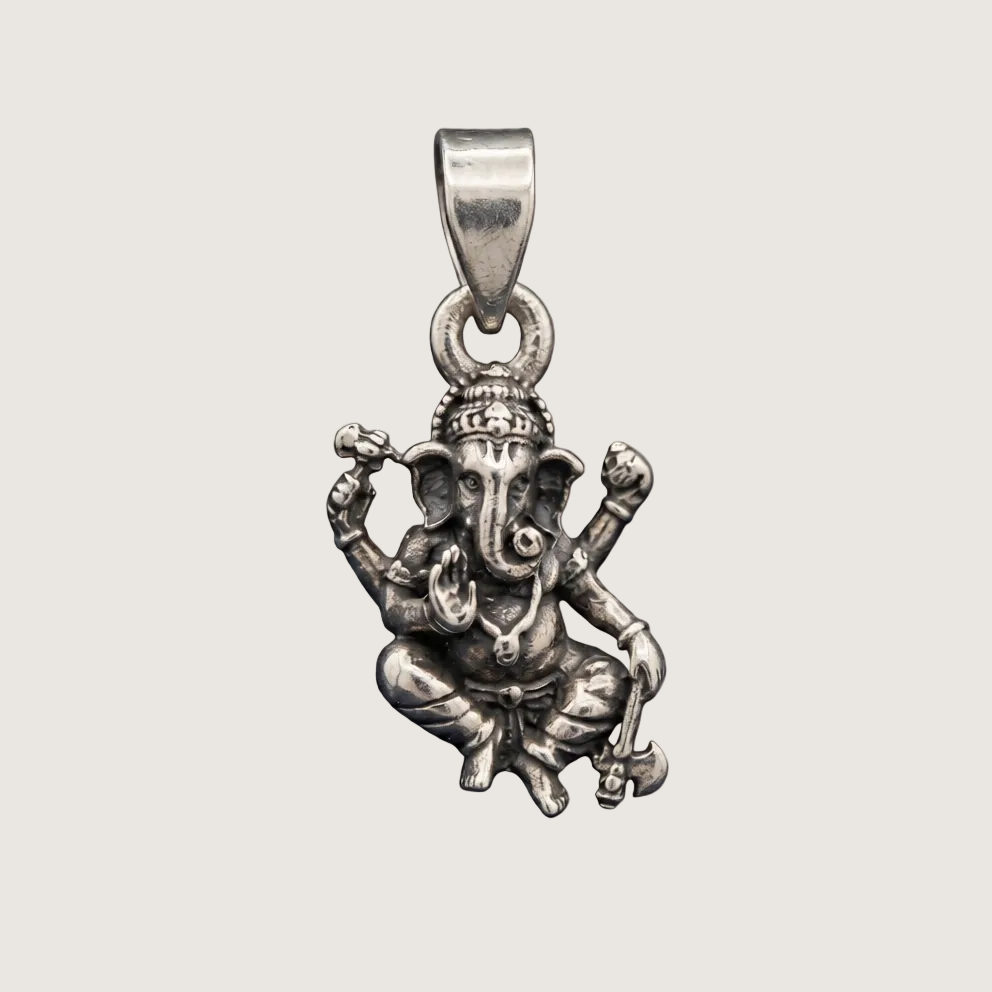 Silver pendant of a seated figure with outstretched arms on a beige background