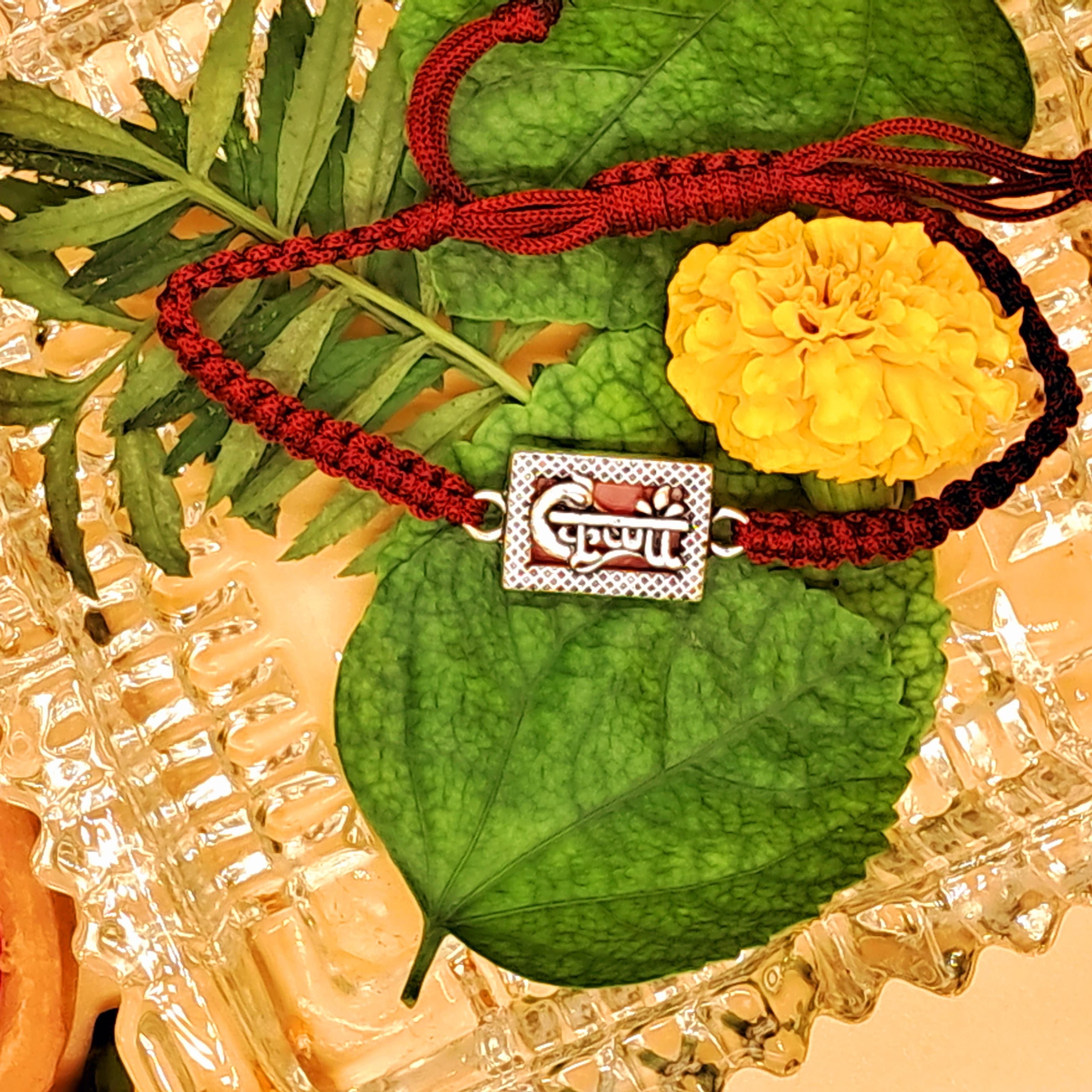 Decorative pendant with red cord on green leaves against a textured background