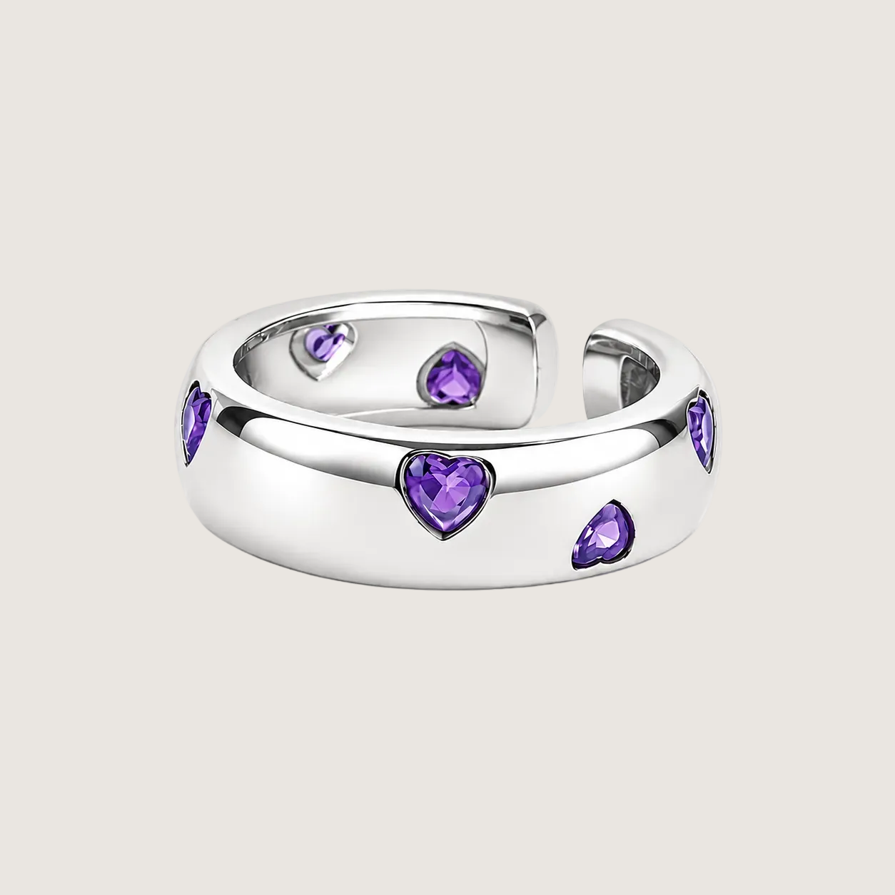 Silver ring with purple heart-shaped gemstones on a light pink background